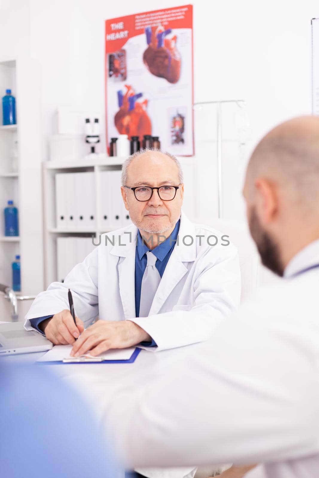 Mature male doctor in hospital conference room by DCStudio