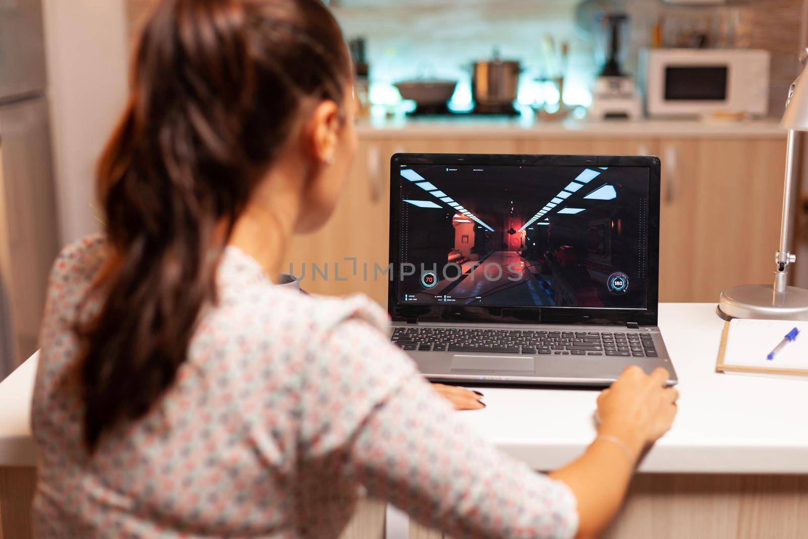 Lady playing games on laptop during night time by DCStudio