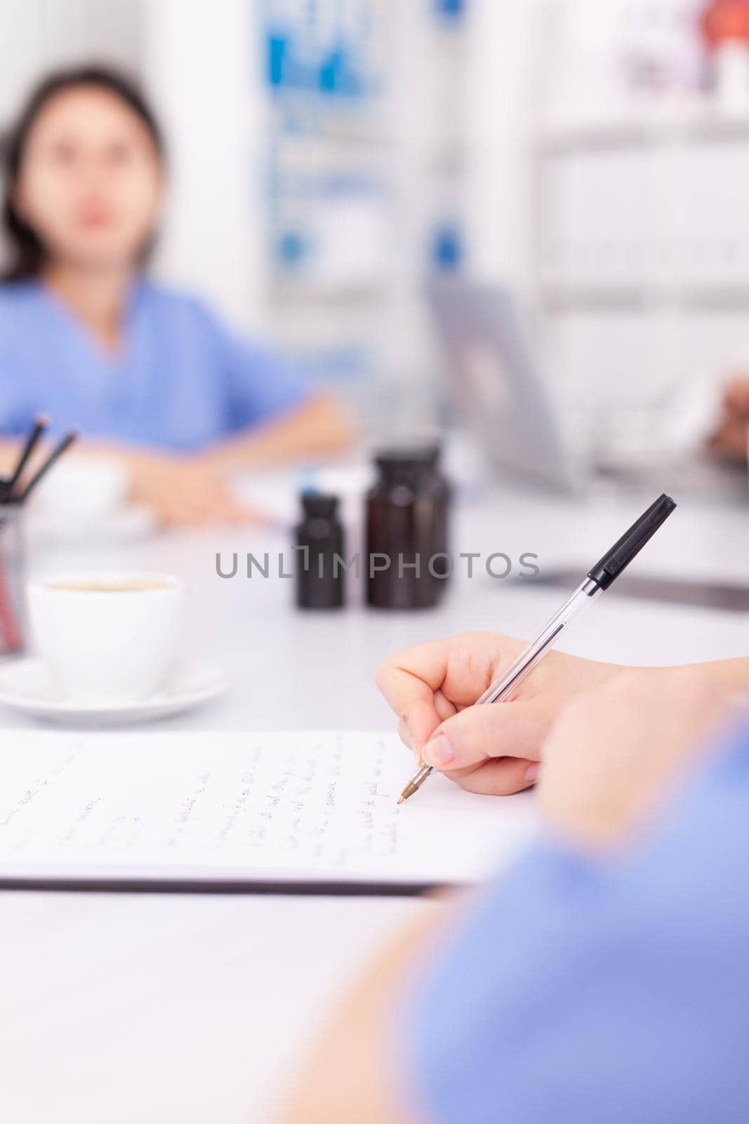Medical nurse writing on clipboard during healthcare seminar in hospital meeting office about technology. Clinic expert therapist talking with colleagues about disease, medicine professional.