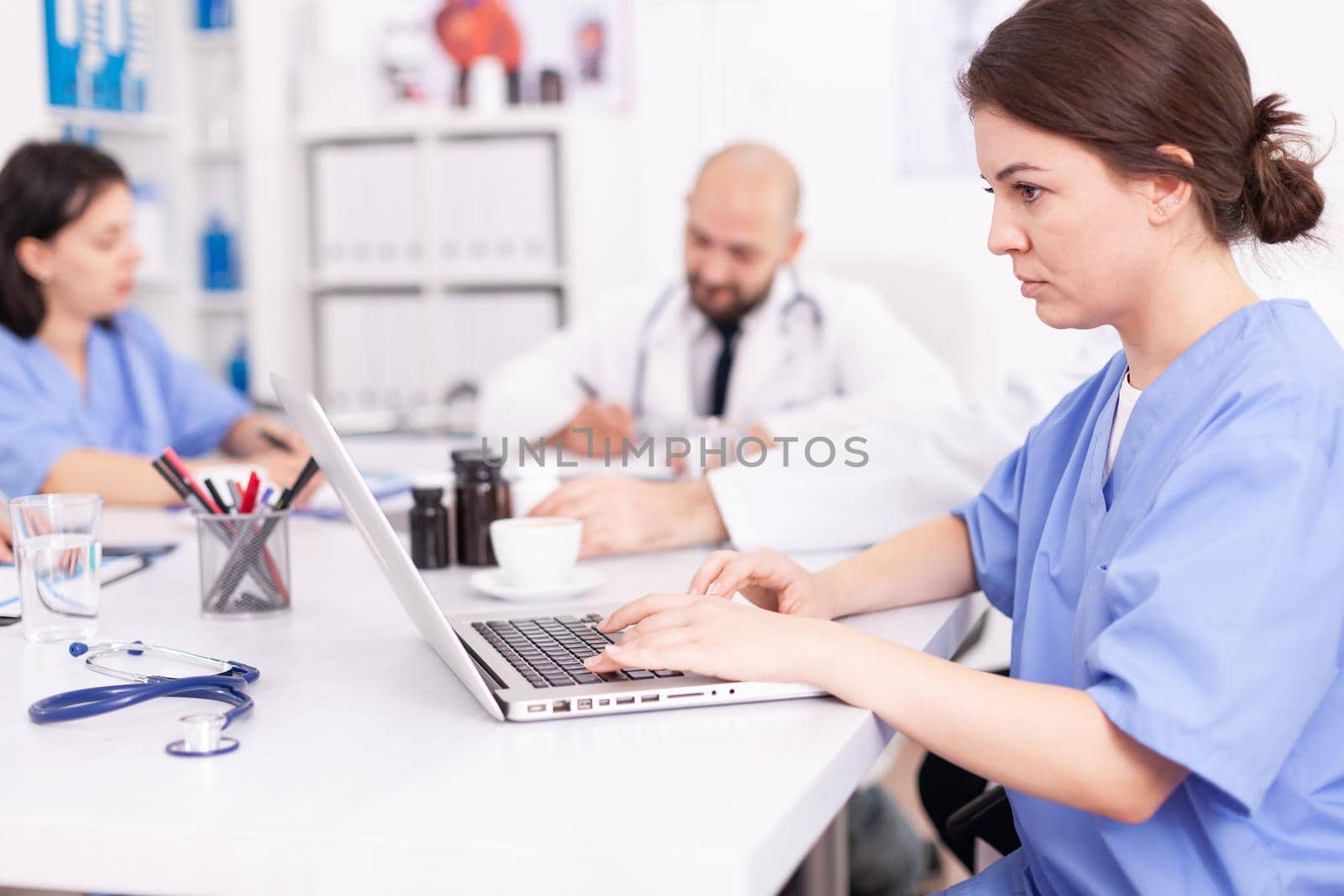 Close up of healthcare physician taking notes on laptop during medical seminar with medicine experts. Clinic therapist talking with colleagues about disease, medicine professional