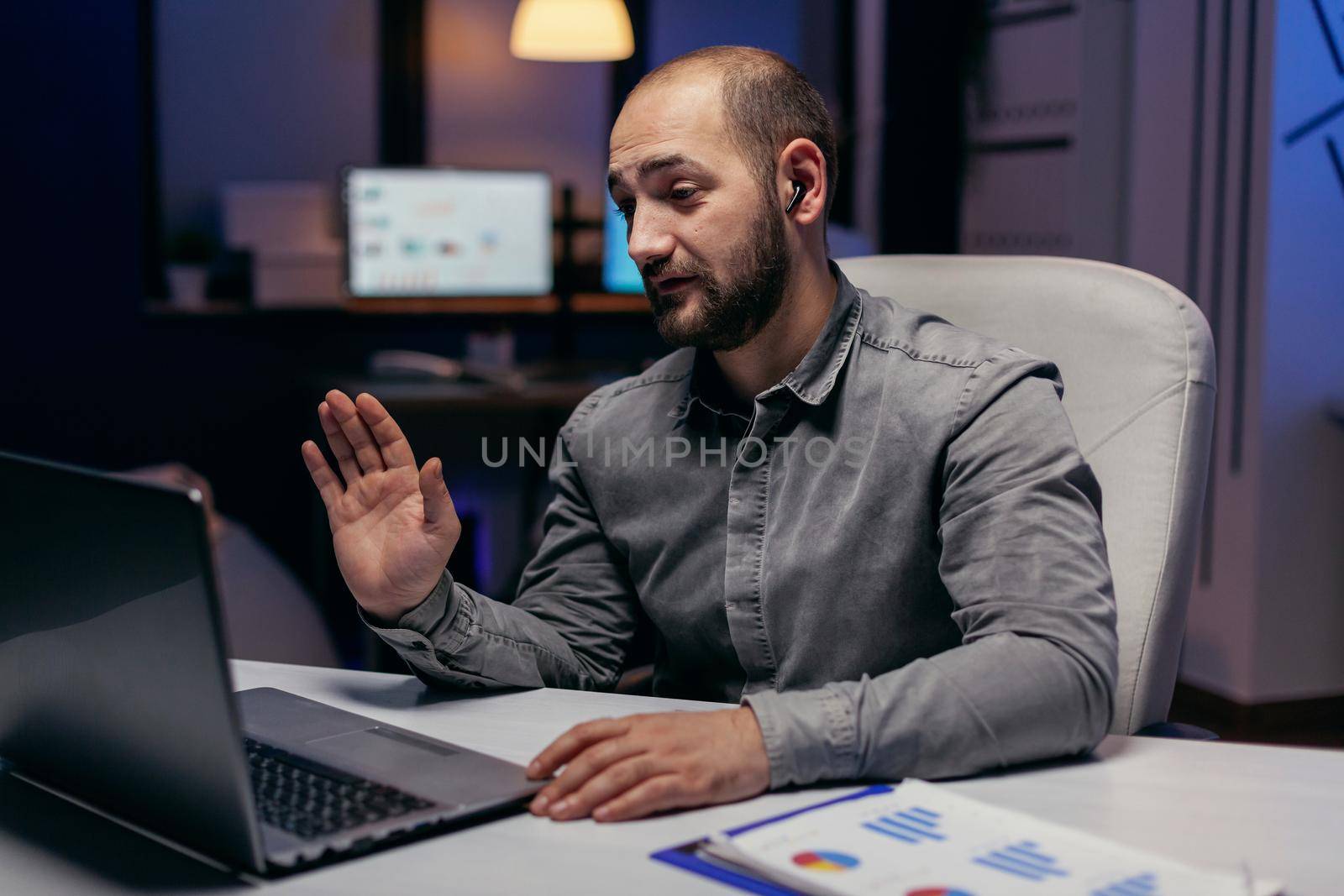 Entrepreneur greeting people during online call to talk about future project. Businessman in the course of an important video conference while doing overtime at the office.