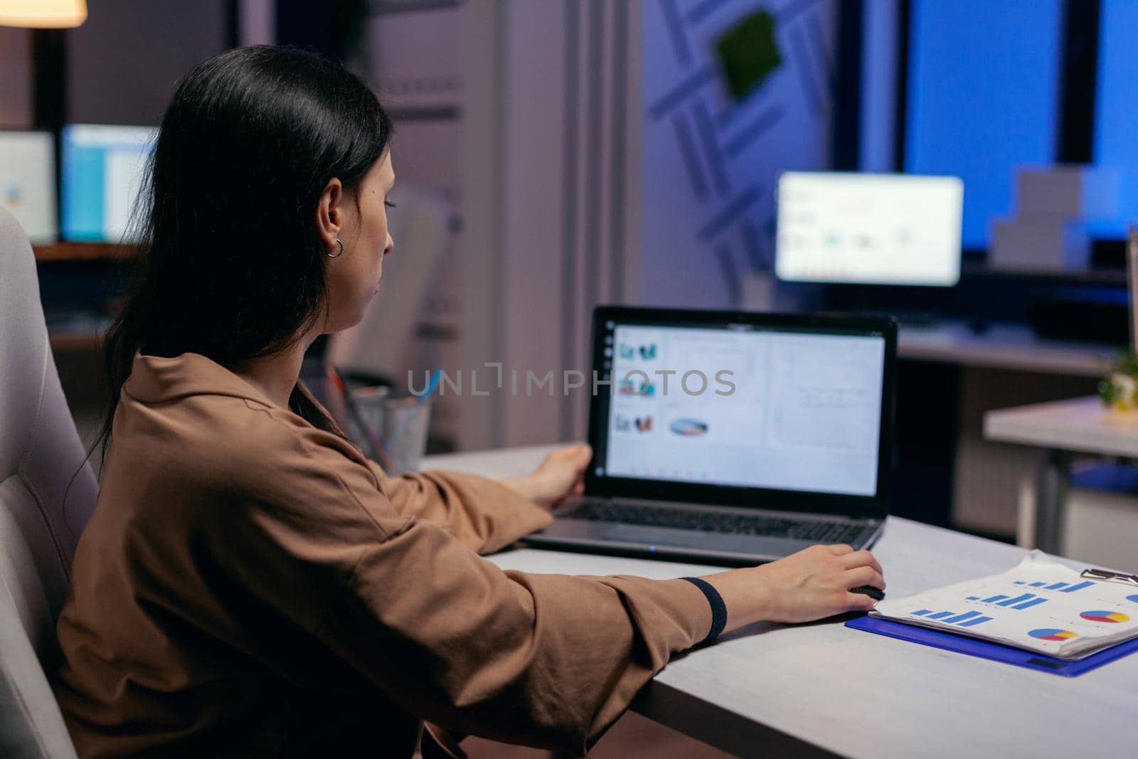 Focused entrepreneur checking business reports trying to finish a deadline. Businesswoman looking at statistics on laptpop screen sitting at her workplace doing overtime.