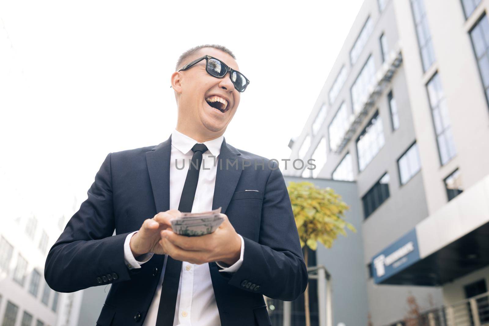 Successful business man counting money. Smiling man enjoy good deal near modern office. Man made easy money. Rich man in stylish suit wearing sunglasses counting money