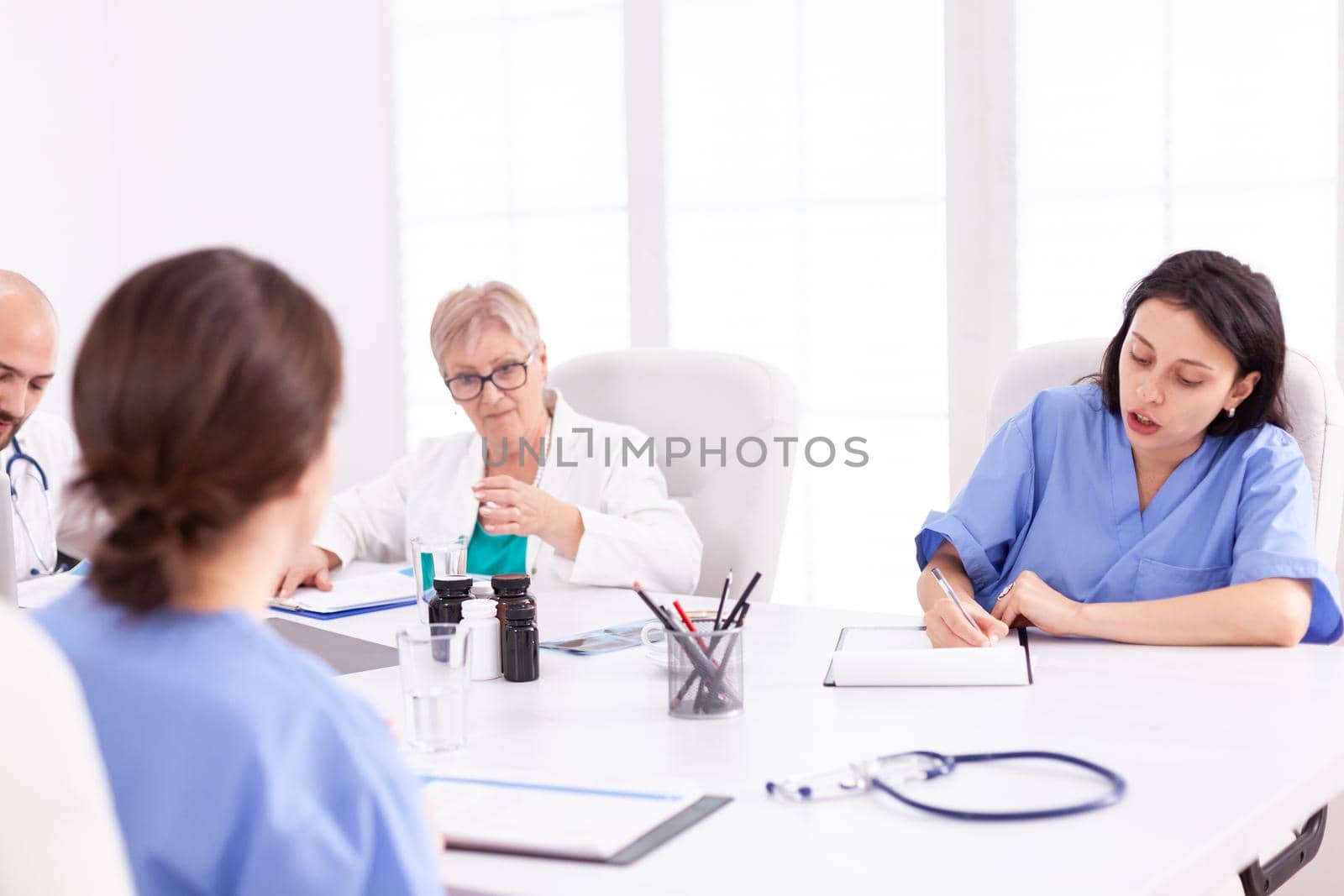 Doctors having a medical discussion with her staff during team meeting. Clinic expert therapist talking with colleagues about disease, medicine professional.