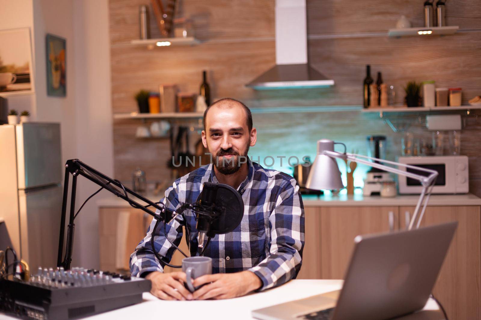 Influencer holding coffee cup and recording podcast in home studio. Creative online show On-air production internet broadcast host streaming live content, recording digital social media communication