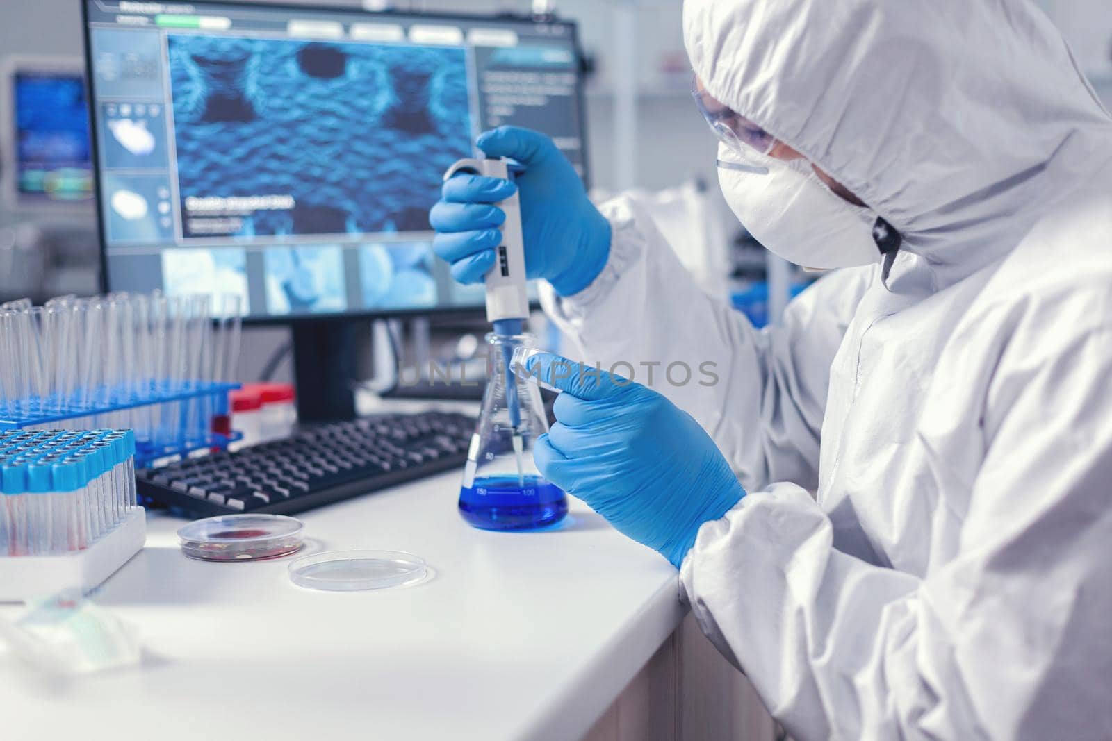 Man in scientific lab working with micropipette and petri dish during global pandemic. Chemist in modern laboratory doing research using dispenser during global epidemic with covid-19.