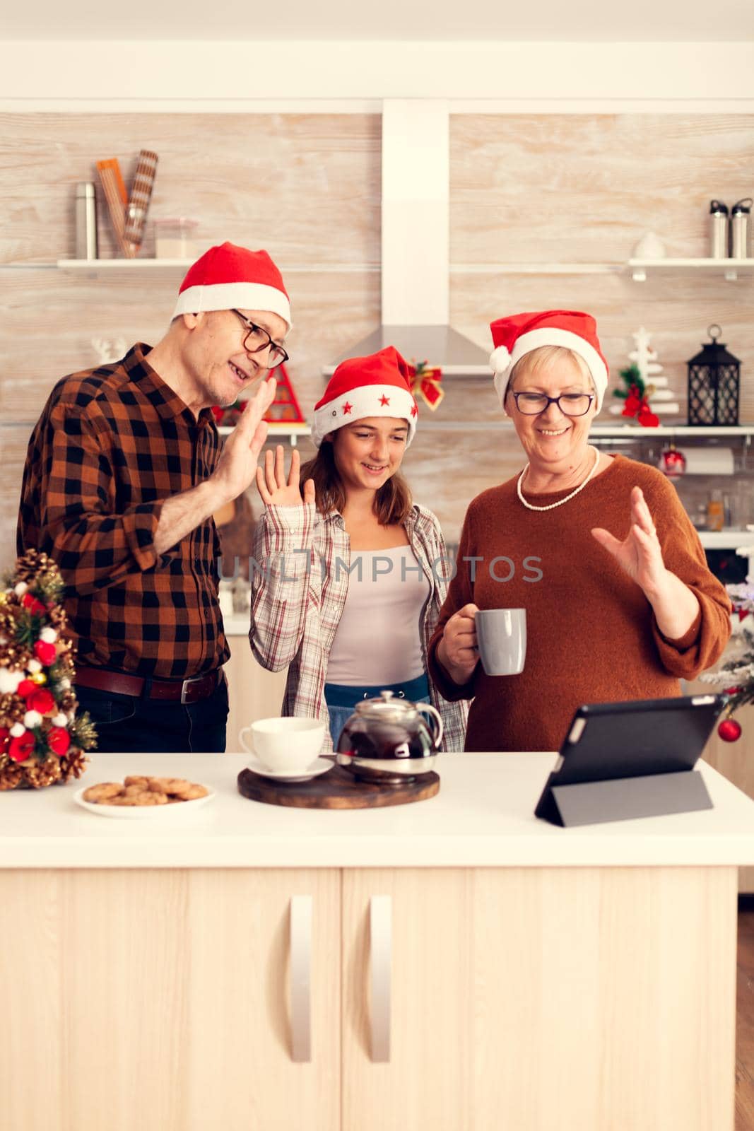 Chereful grandchild having a conversation with parents during christmas on tablet pc. by DCStudio