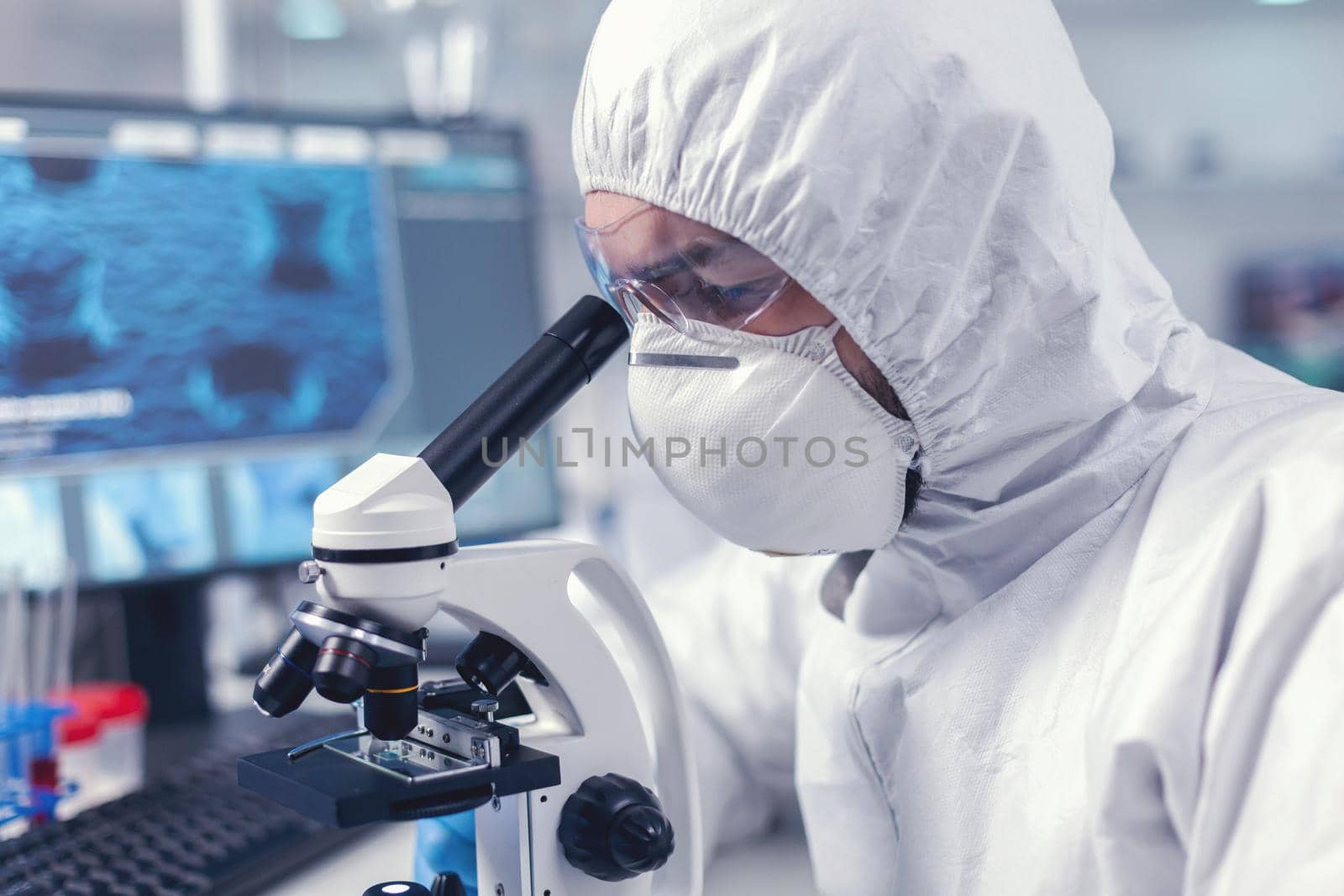 Doctor developing vaccine using microscope in modern laboraory. Virolog in coverall during coronavirus outbreak conducting healthcare scientific analysis.