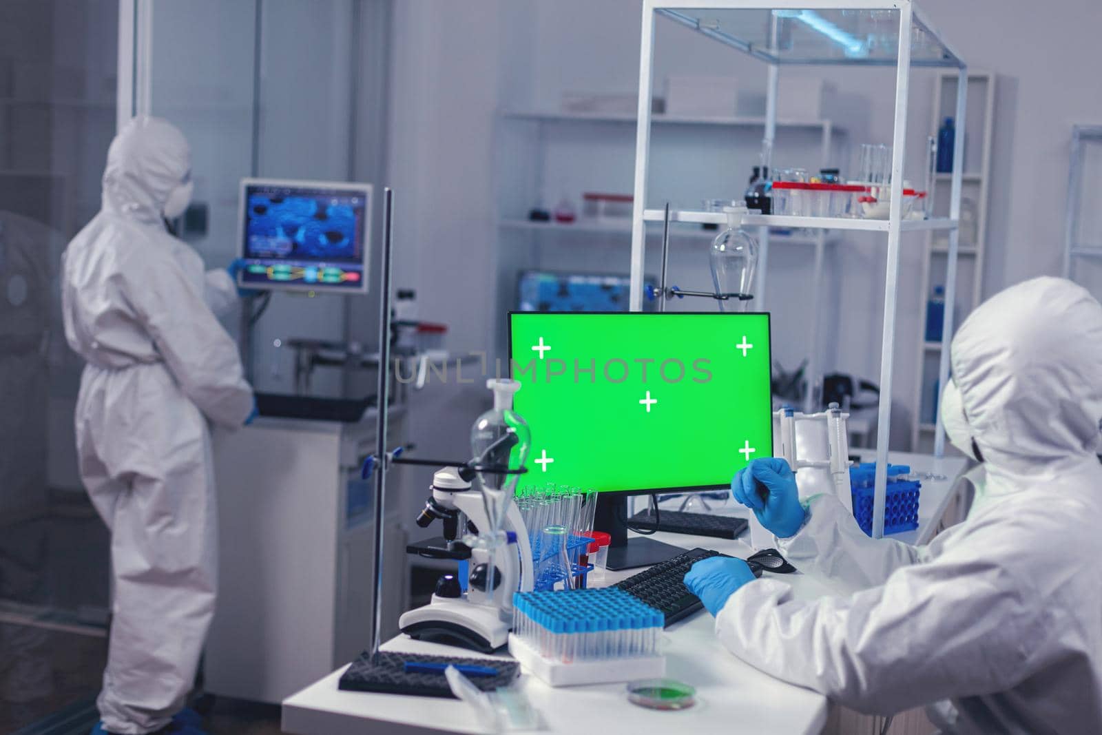 Scientist typing on keyboard works with computer with green screen dressed in ppe. Team of microbiologists doing vaccine research writing on device with chroma key, isolated, mockup display.
