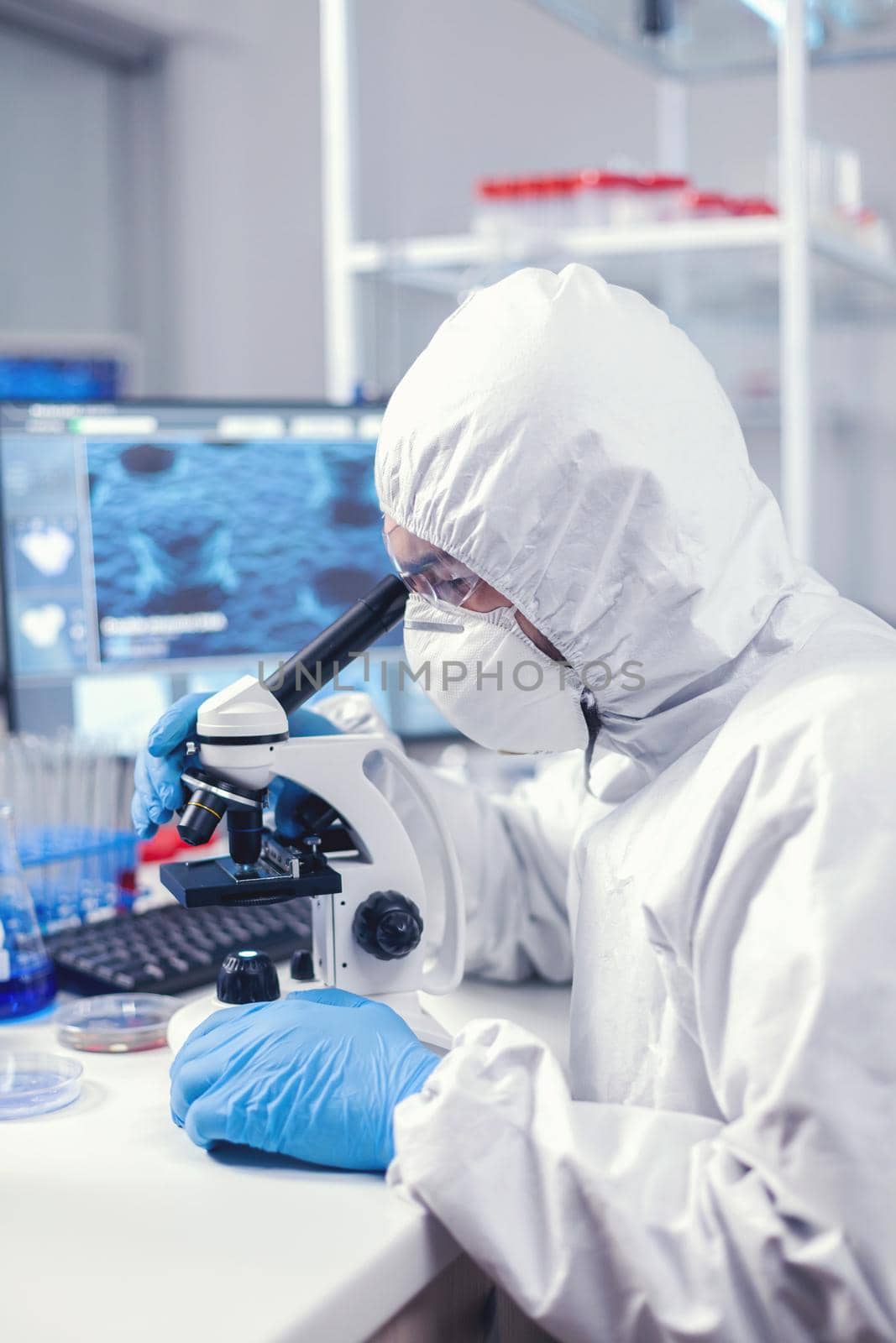 Scientist using modern laboratory equipment dressed in protection against covid19. Virolog in coverall during coronavirus outbreak conducting healthcare scientific analysis.