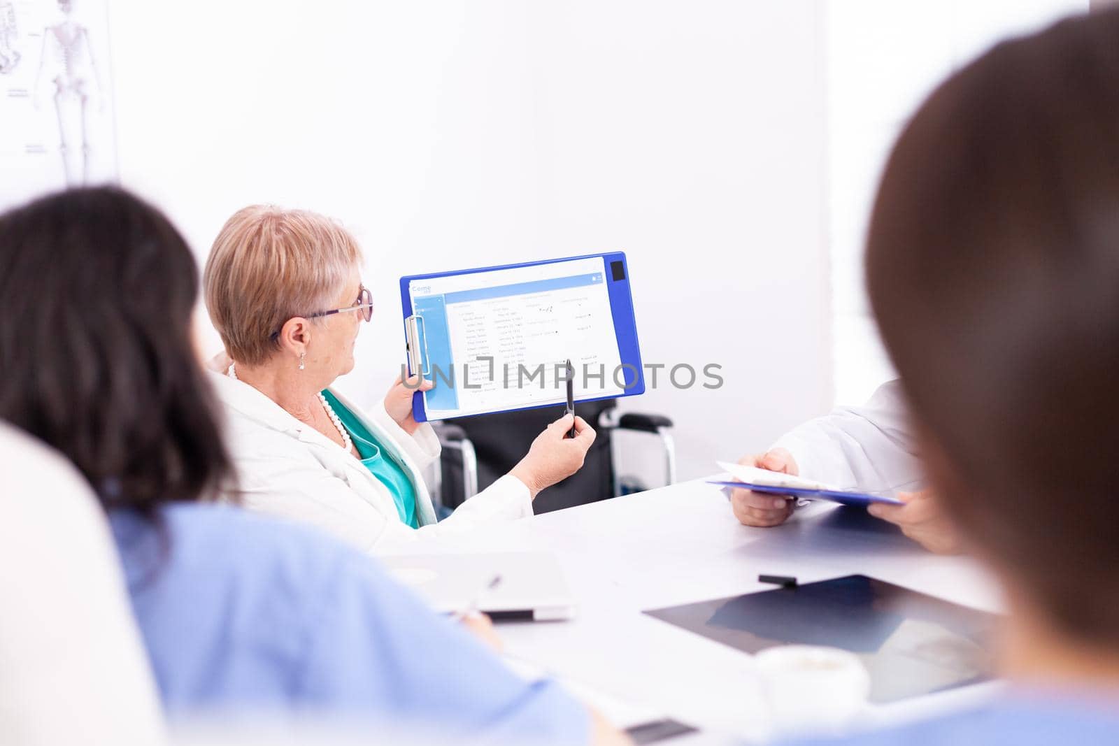 Group of doctors sitting at desk by DCStudio