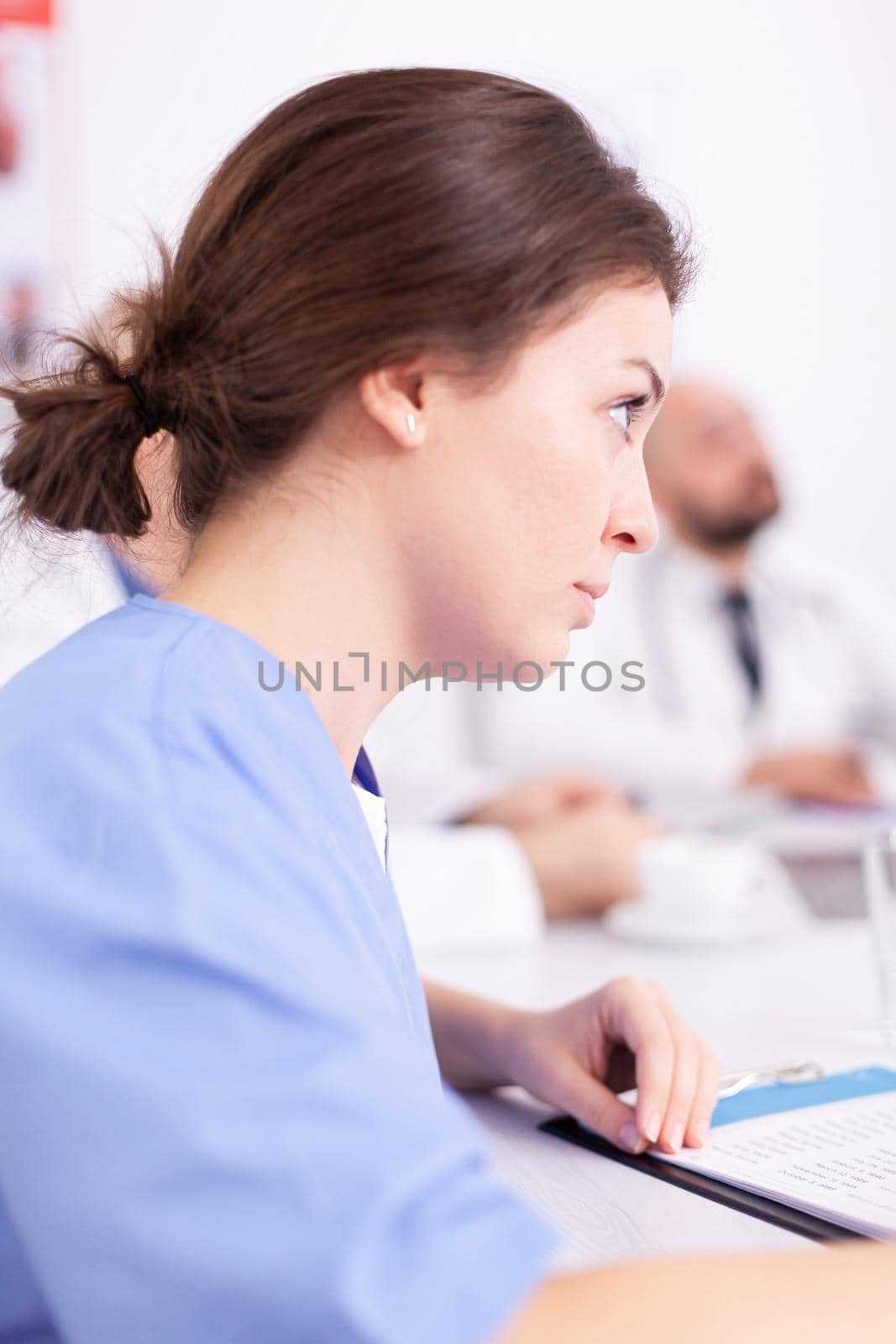Portrait of medical nurse paying attention during healthcare seminar in hospital conference room. Clinic expert therapist talking with colleagues about disease, medicine professional