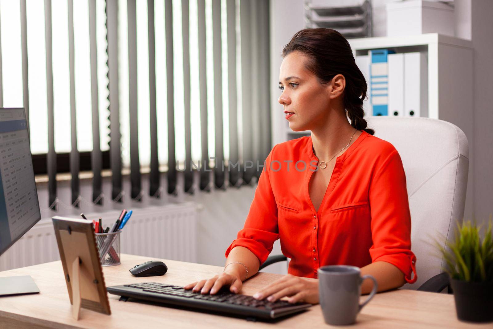 Executive businesswoman in workplace office working on finance corporate project. Successful concentrated employer with busy carreer sitting at desk in office using modern pc.