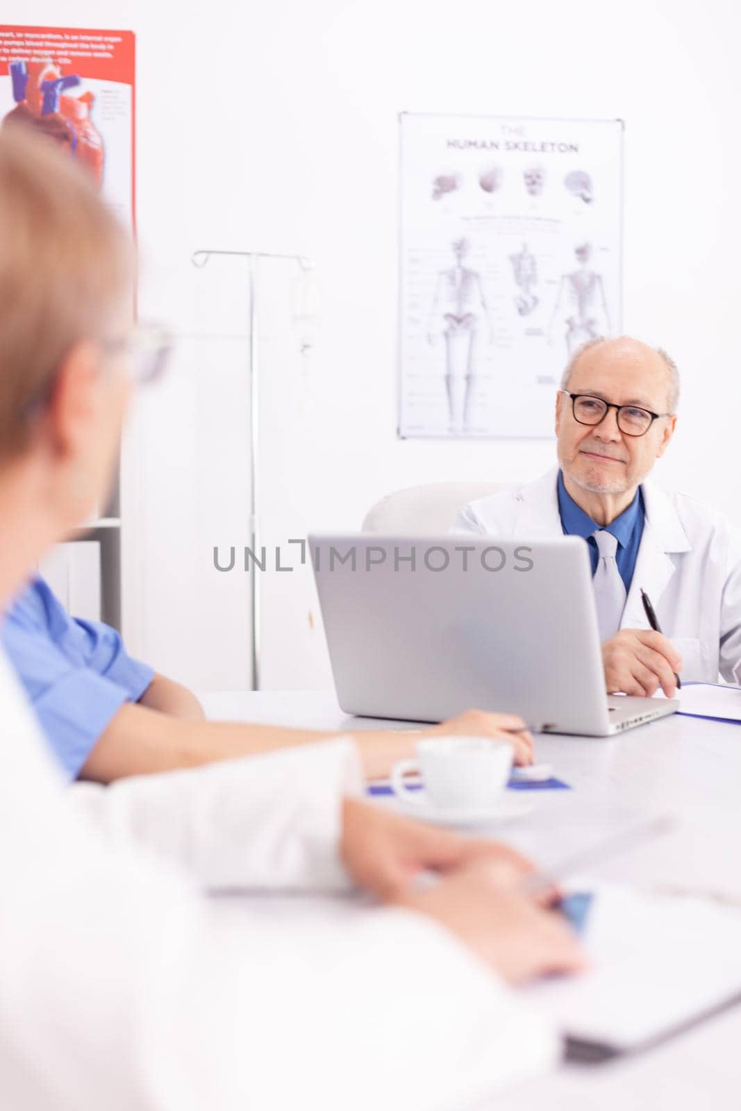 Medical expert talking with medical staff during healthcare meeting in hospital conference room. Clinic therapist talking with colleagues about disease, medicine professional