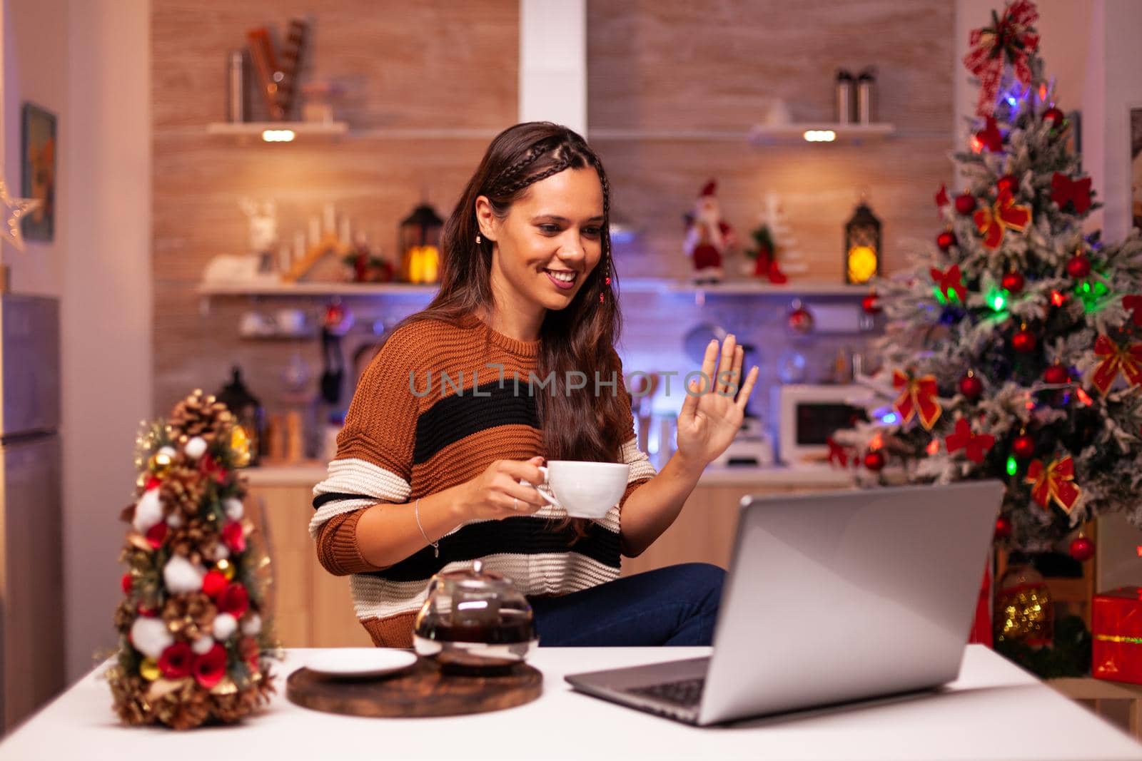 Young woman holding cup of tea using video call concept by DCStudio