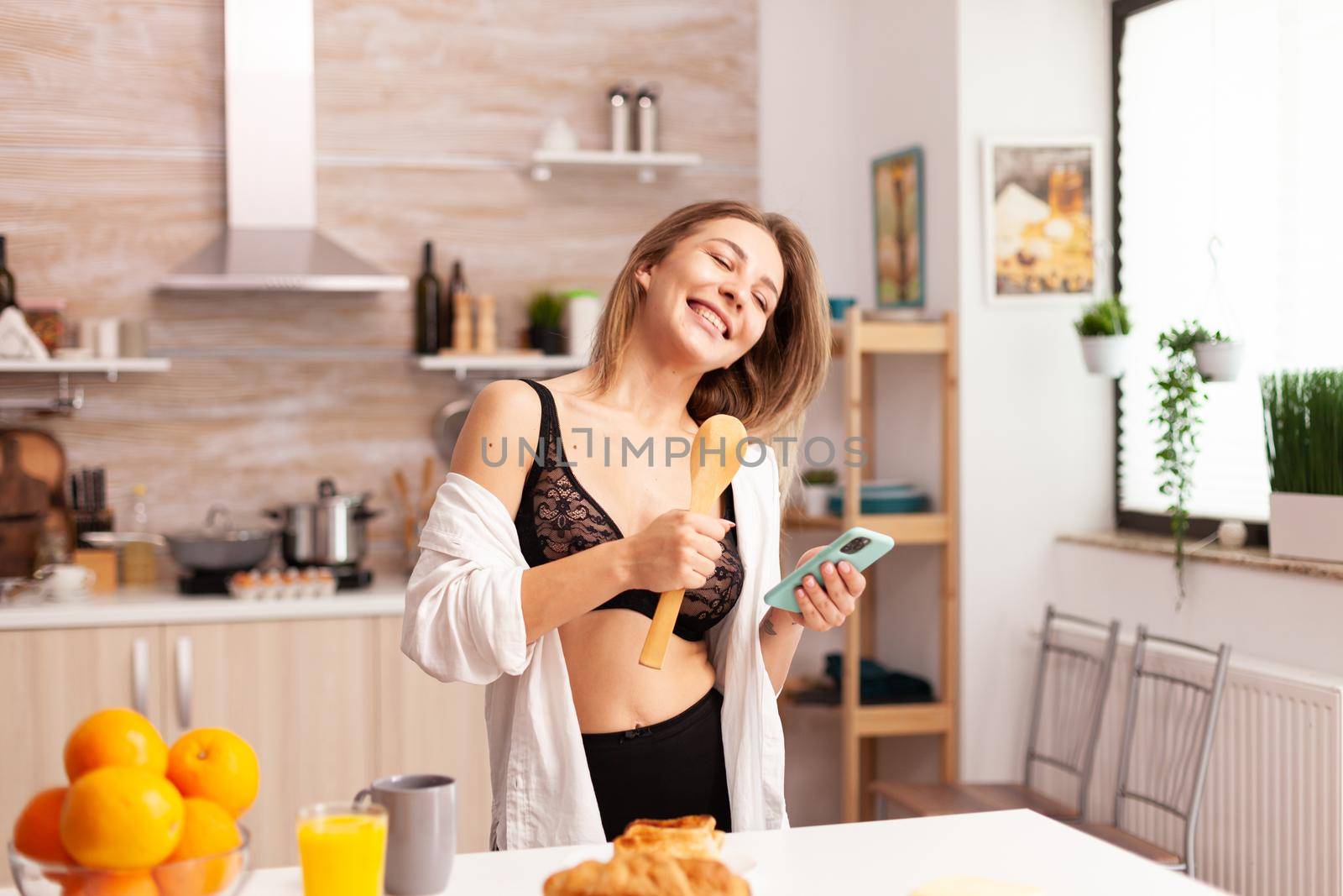 Woman having fun singing in kitchen by DCStudio