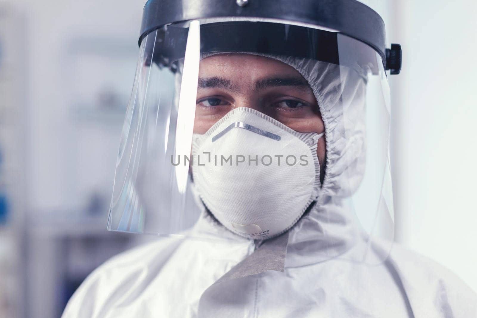 Close up of wearied chemist in laboratory wearing ppe equipment during mondial outbreak with covid19. Overworked researcher dressed in protective suit against invection with coronavirus during global epidemic.
