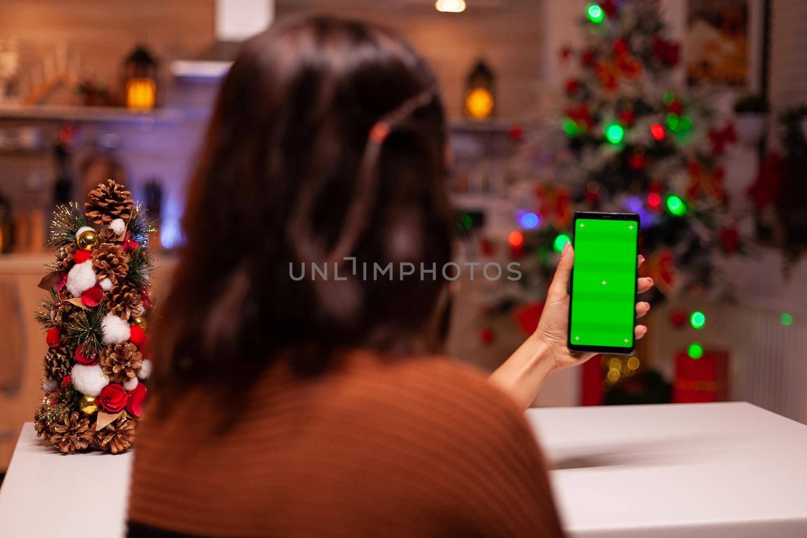 Festive person holding smartphone with green screen by DCStudio