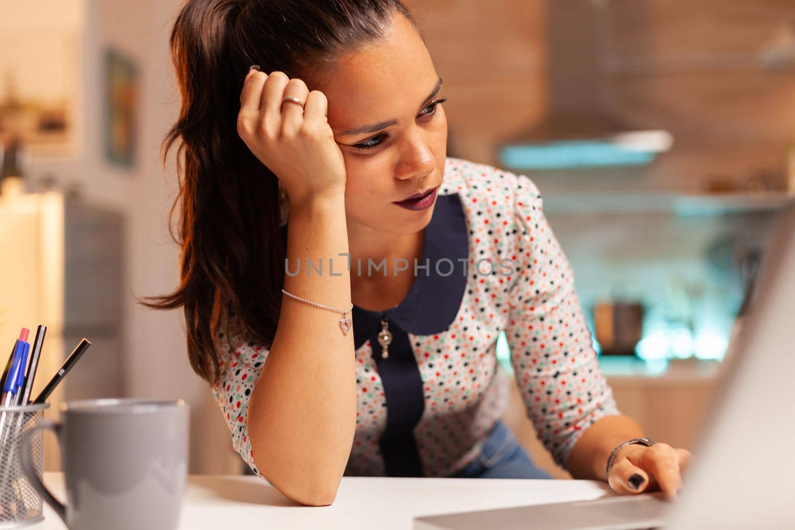 Female entrepreneur reading emails on laptop sitting on desk in home kitchen, Employee using modern technology at midnight doing overtime for job, business, busy, career, network, lifestyle ,wireless.