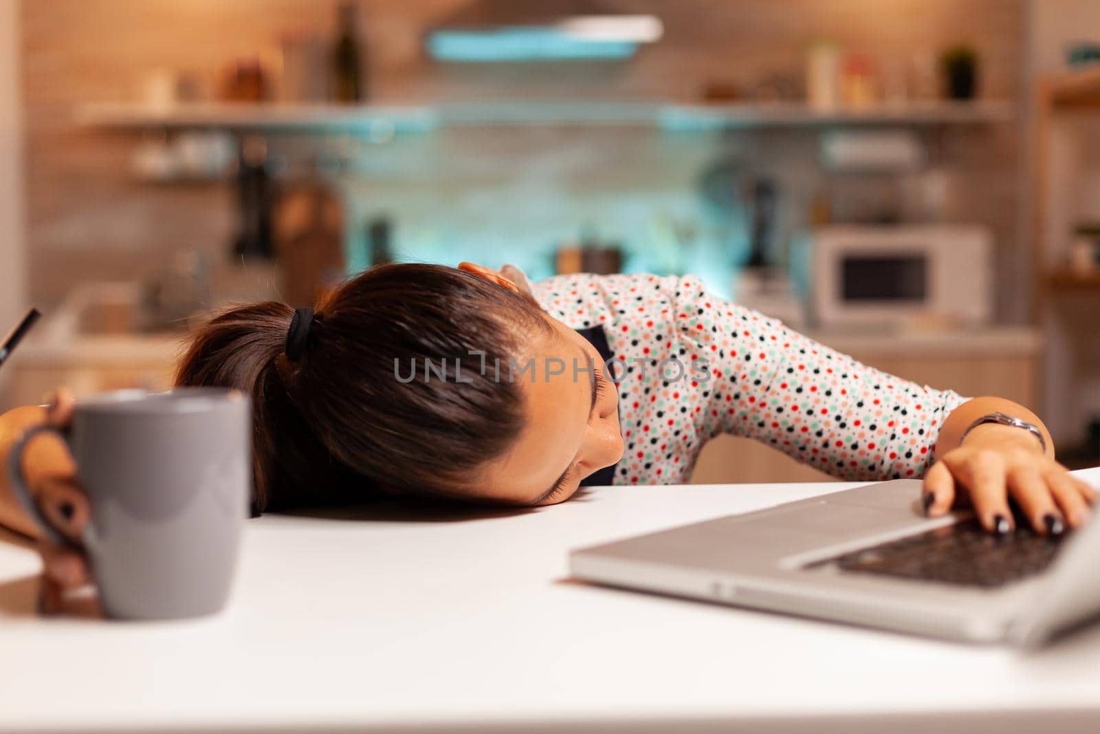 Freelance woman falling asleep in home kitchen working overtime on a project. Employee using modern technology at midnight doing overtime for job, business, busy, career, network, lifestyle ,wireless.