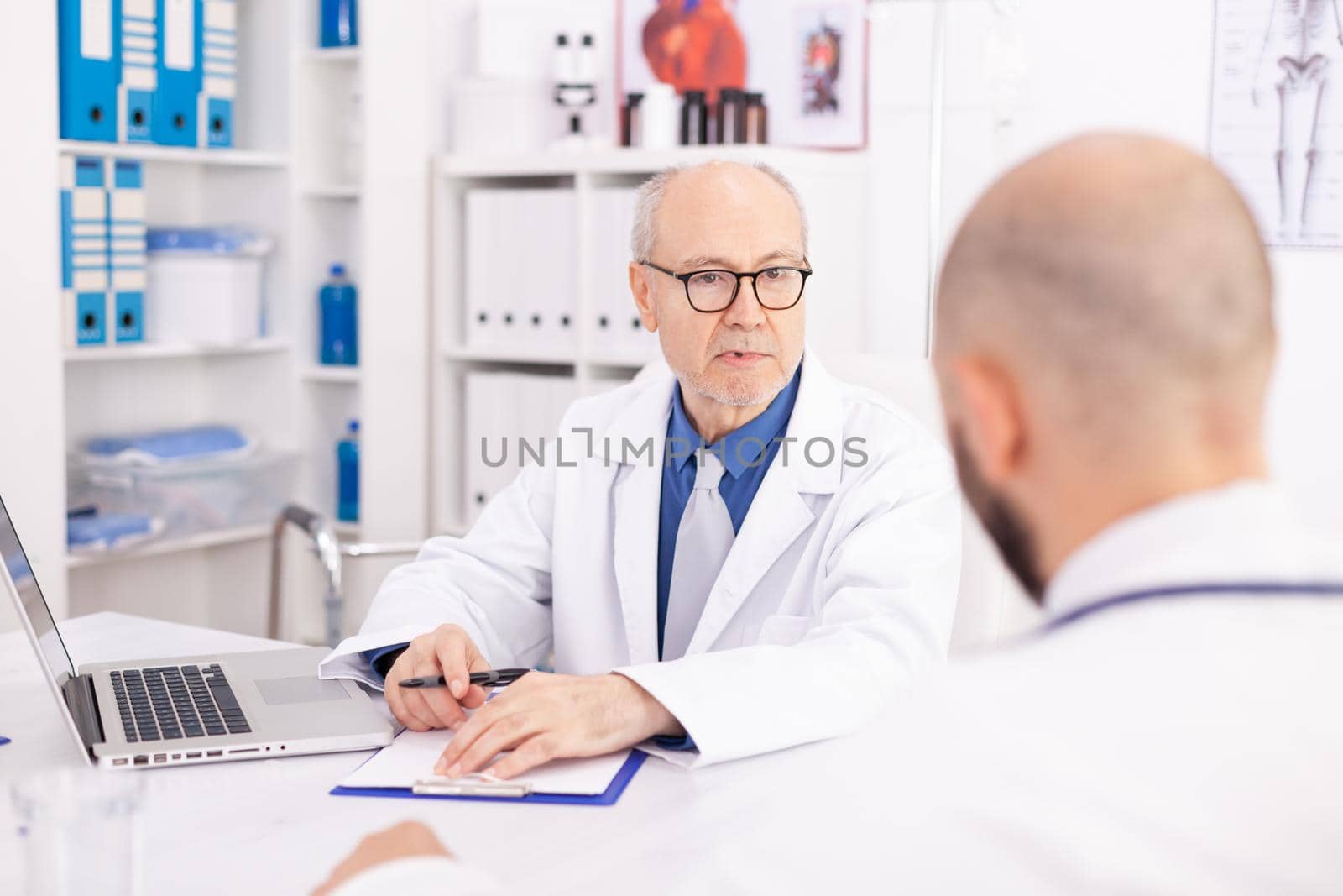 Experienced mature doctor explaining diagnosis by DCStudio