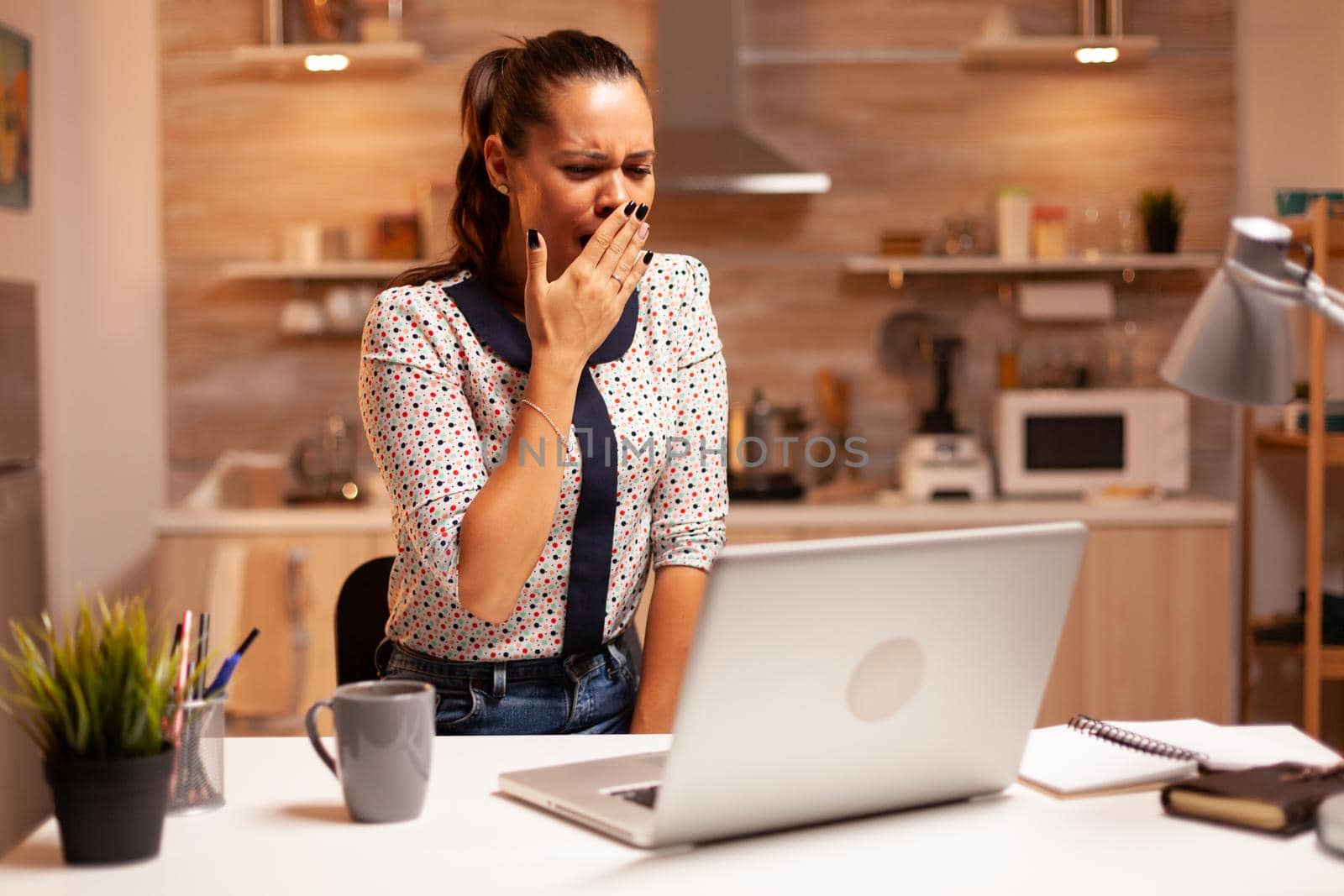 Businesswoman yawning during deadline by DCStudio