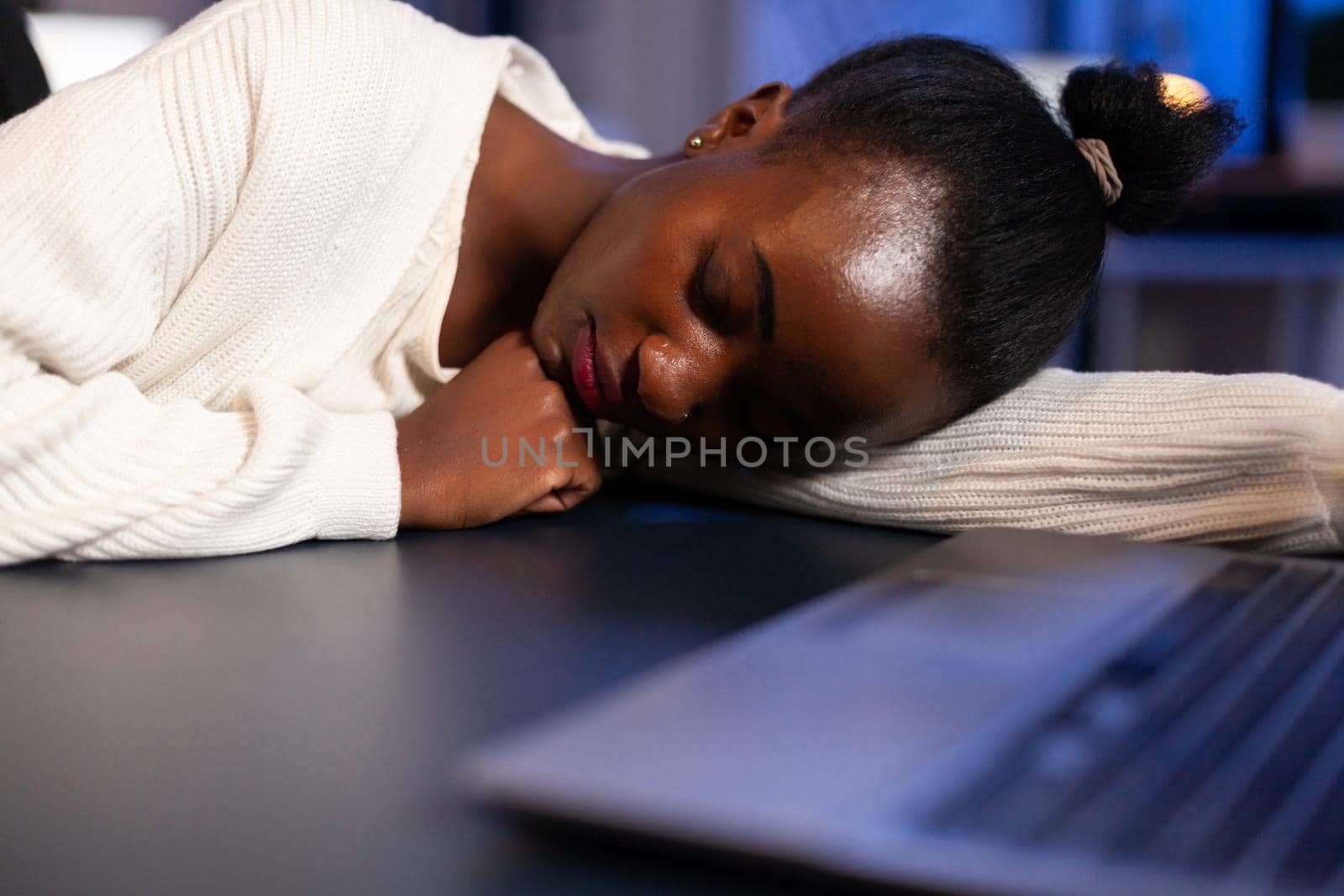 Exhausted overload african business woman falling asleep on desk with open laptop monitor while working in start up company. Overworked employee using doing overtime respecting deadline.