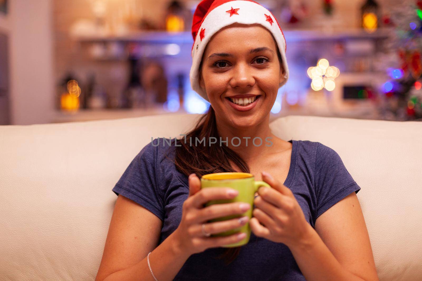 Portrait of woman wearing red santa hat holding cup of coffee in hands by DCStudio