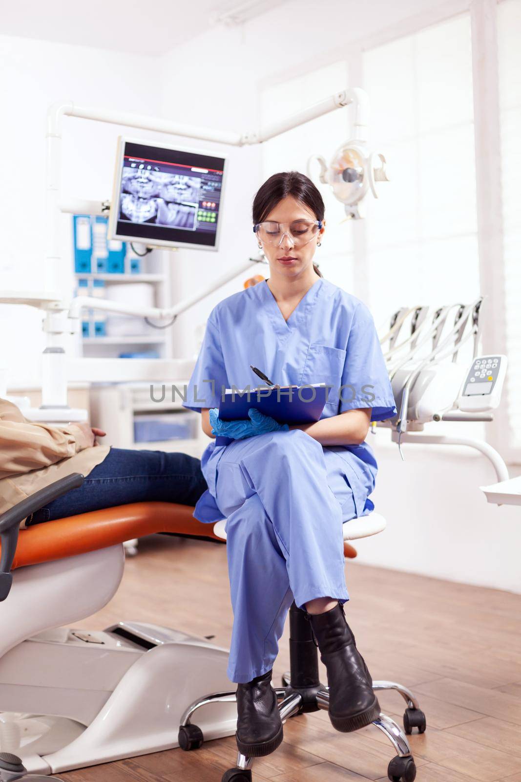 Dental assistant taking notes on clipboard in dentist clinic by DCStudio
