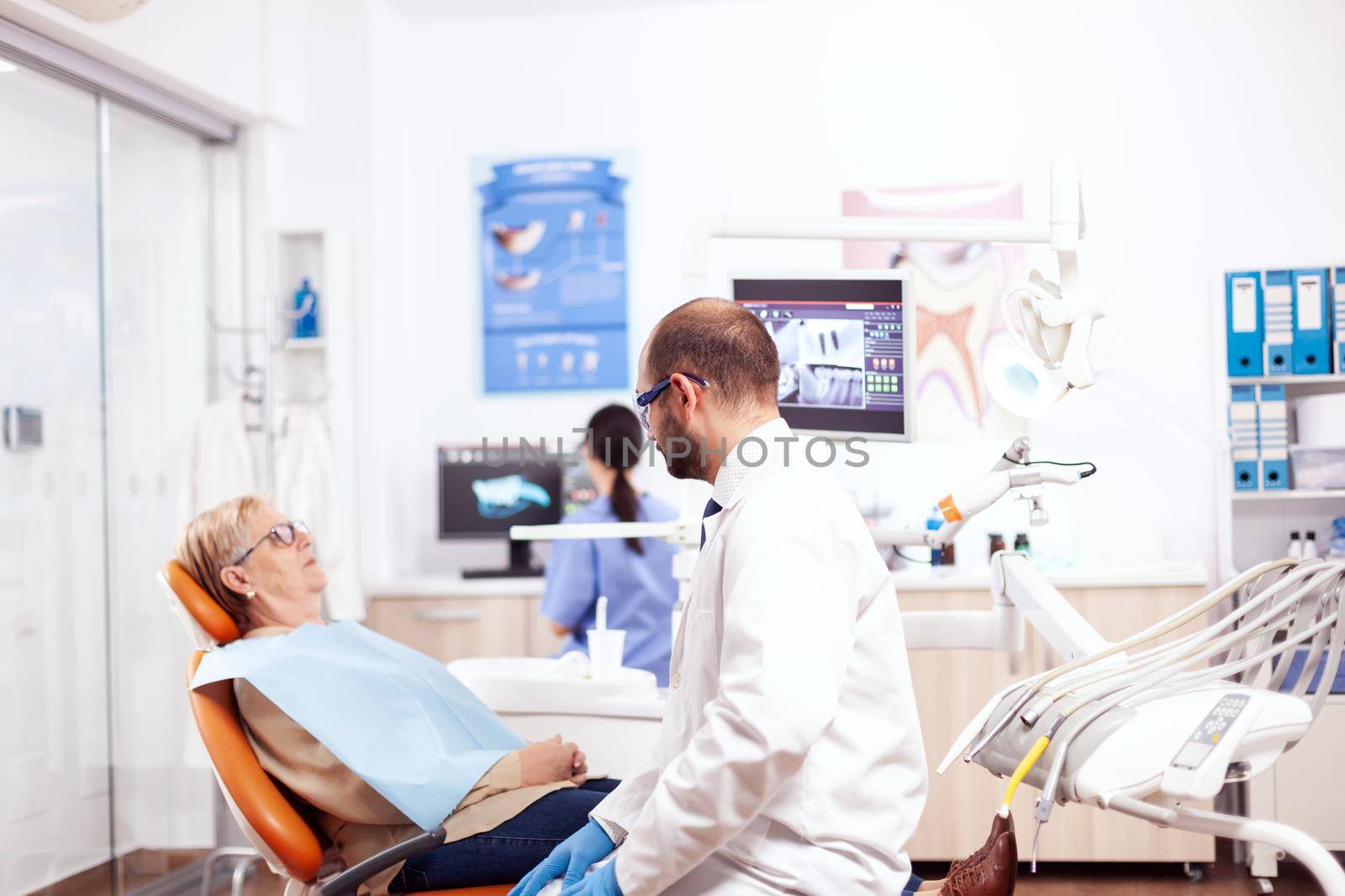Dentist in dental clinic saying diagnostic to senior woman by DCStudio