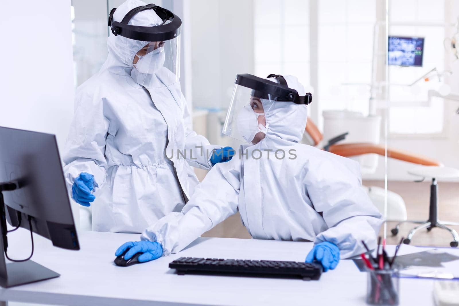 Women doctors in protective suit to fight pandemic with covid-19 in dental reception. Medicine team wearing protection gear against coronavirus pandemic in dental reception as safety precaution.