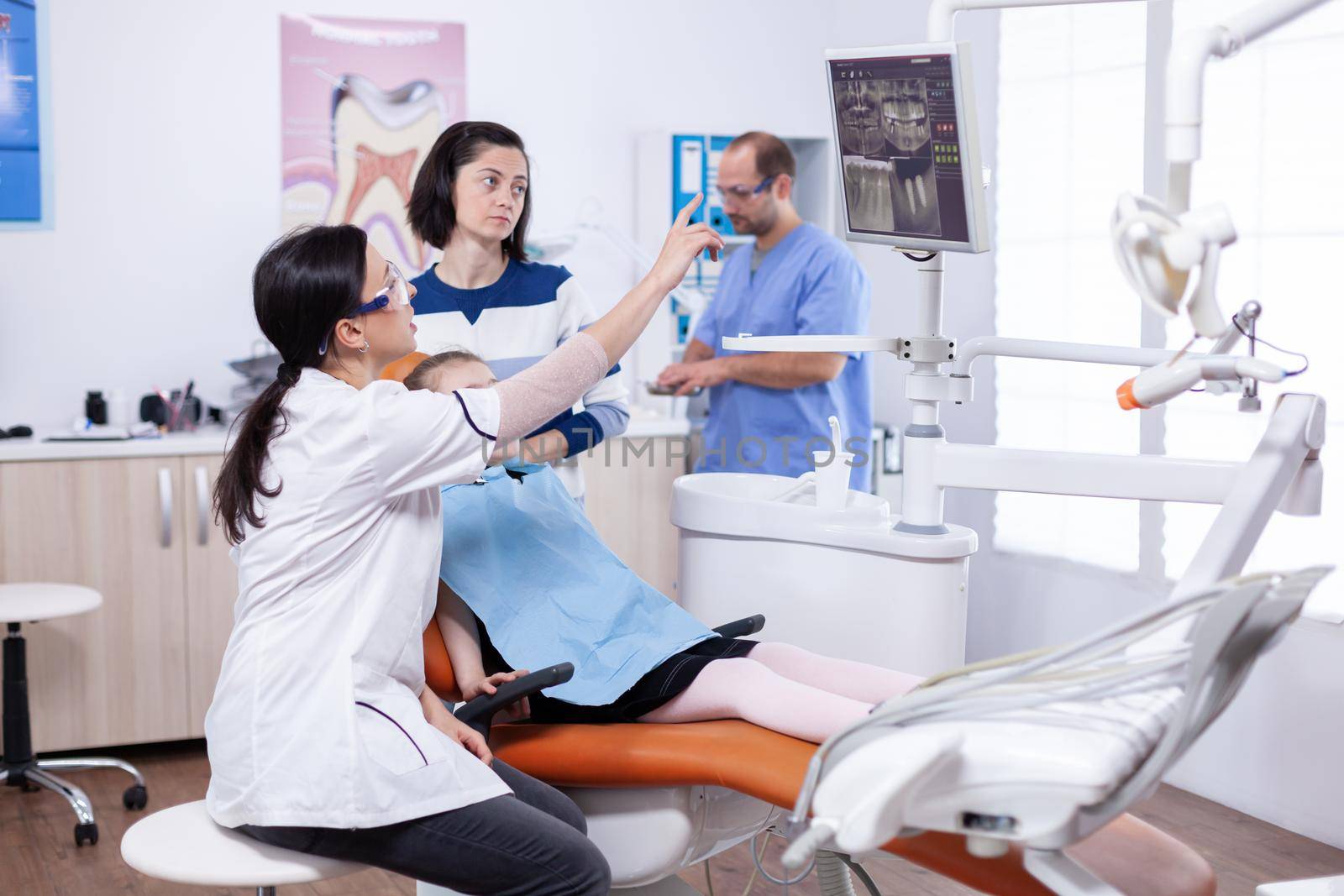 Dentist doctor pointing at caries on dental chair screen by DCStudio