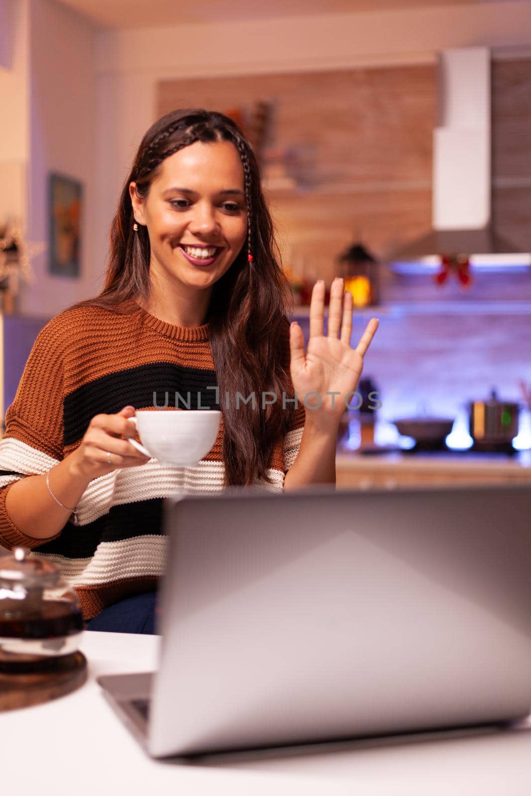 Young woman holding cup of tea using video call concept by DCStudio