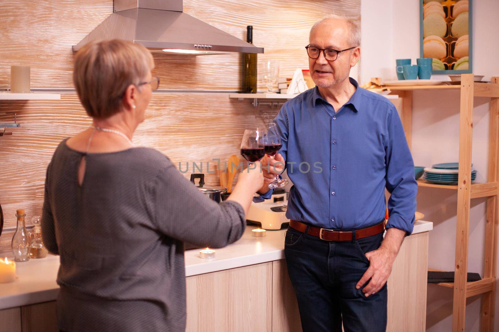 Romantic senior couple sharing memories and toasting with glasses of red wine. Aged couple in love talking having pleasant conversation during healthy meal.