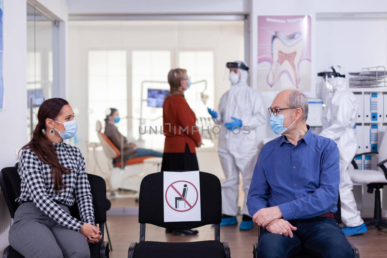Senior man with face mask discussing with woman patient by DCStudio