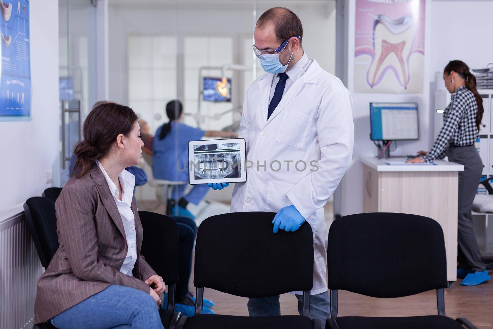 Stomatologist pointing on digital screen explaining x-ray to patient by DCStudio