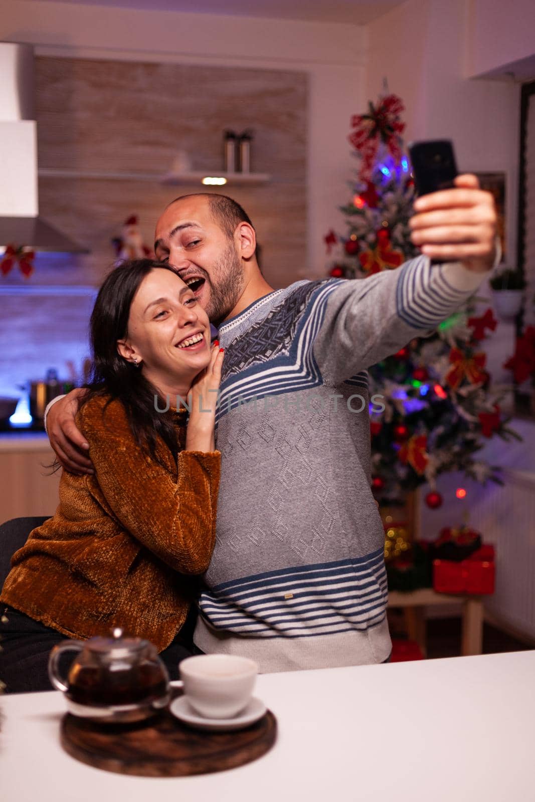 Smiling family taking selfie using smartphone enjoying christmas time standing in xmas kitchen. Happy joyful family celebrating winter holiday season. New year festive season