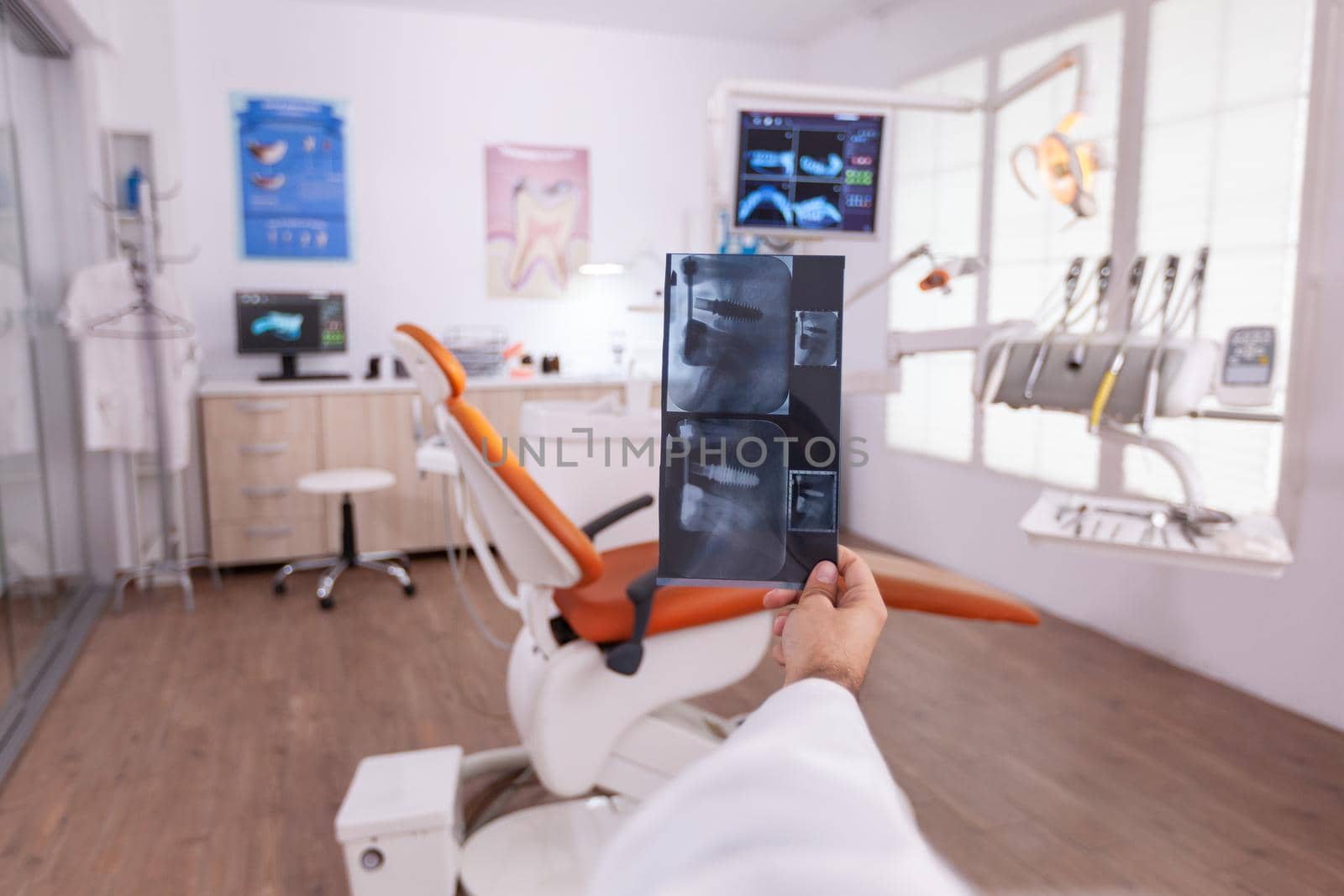 Specialist orthodontist holding medical teeth radiography in hands analyzing oral dental surgery by DCStudio