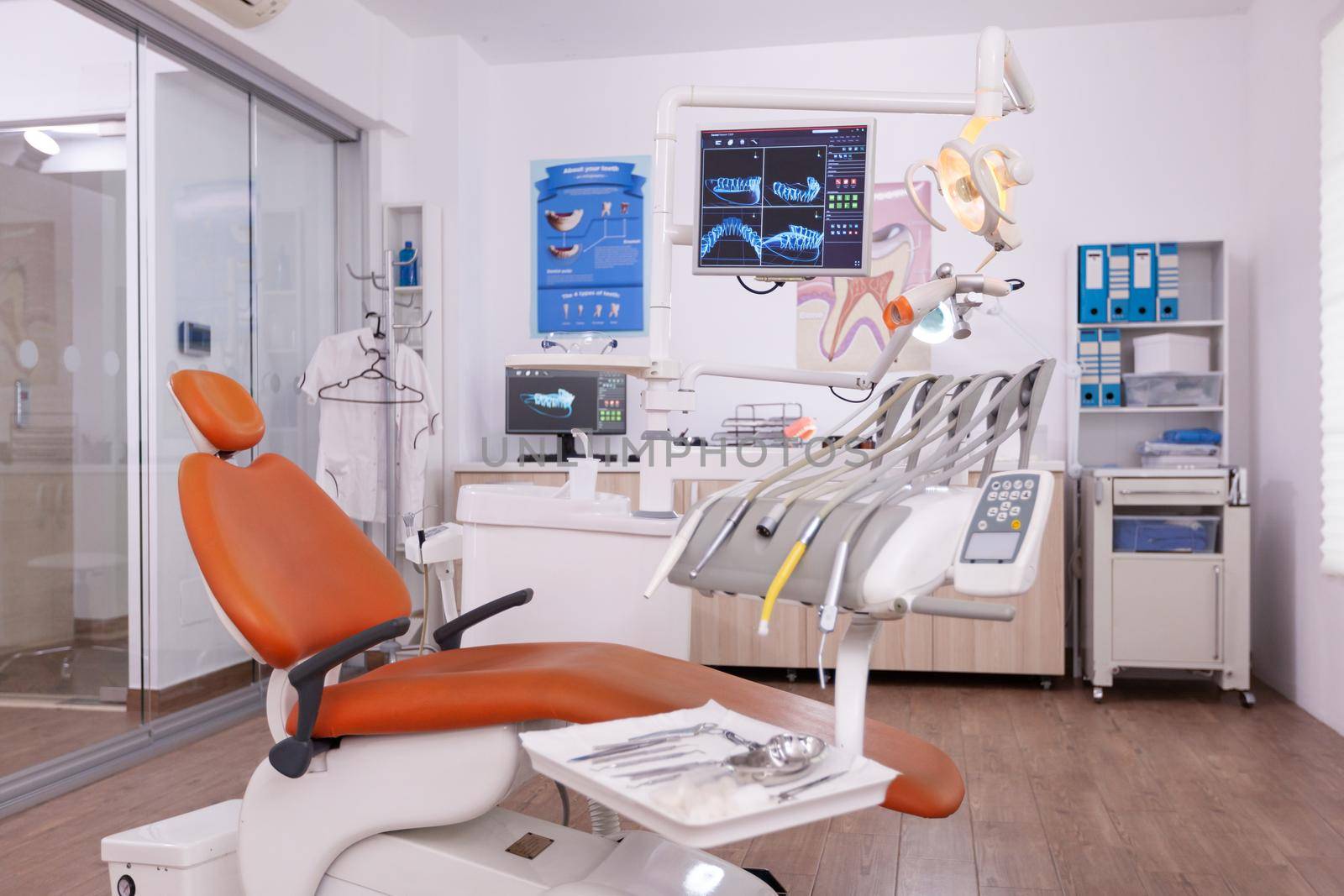 Interior of empty professional dental health office in hospital with stomatology dentistry furniture. Medical workplace cabinet for dental teeth health. Tooth radiography images on monitor