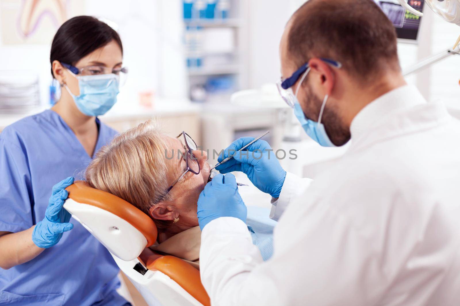 Stomatolog and nurse treats teeth of senior woman by DCStudio