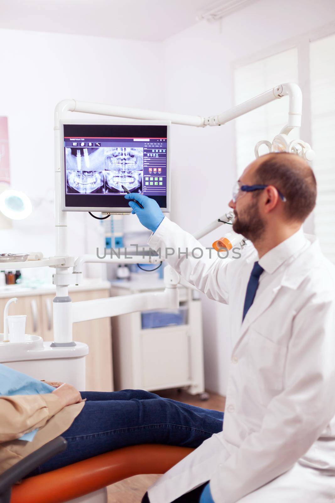 Stomatolog explaining dental treatment to senior woman by DCStudio