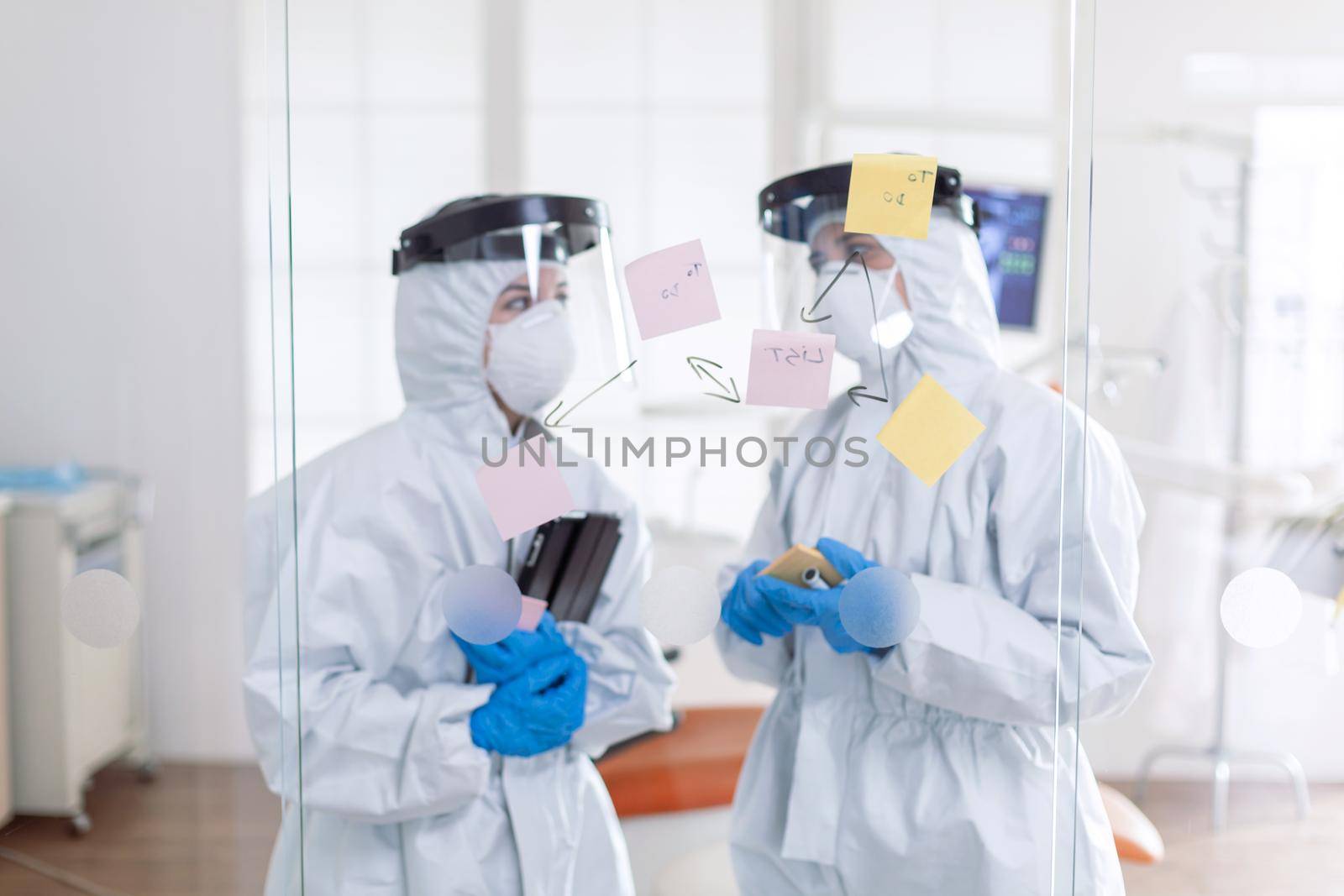 Dentist coworkers talking about teeth issues wearing ppe suit by DCStudio