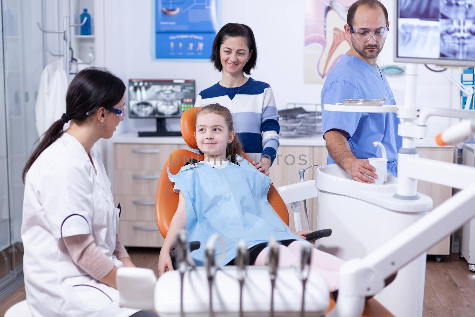 Happy little girl at pediatric dentist wearing dental bib by DCStudio
