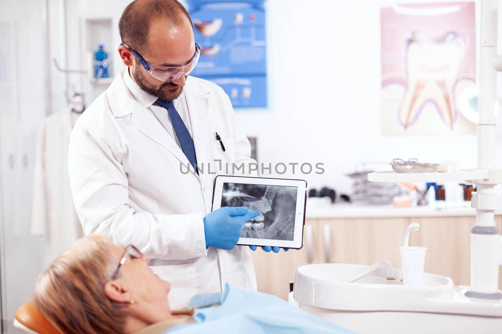 Dentist in dental cabinet explaining tooth diagnosis by DCStudio