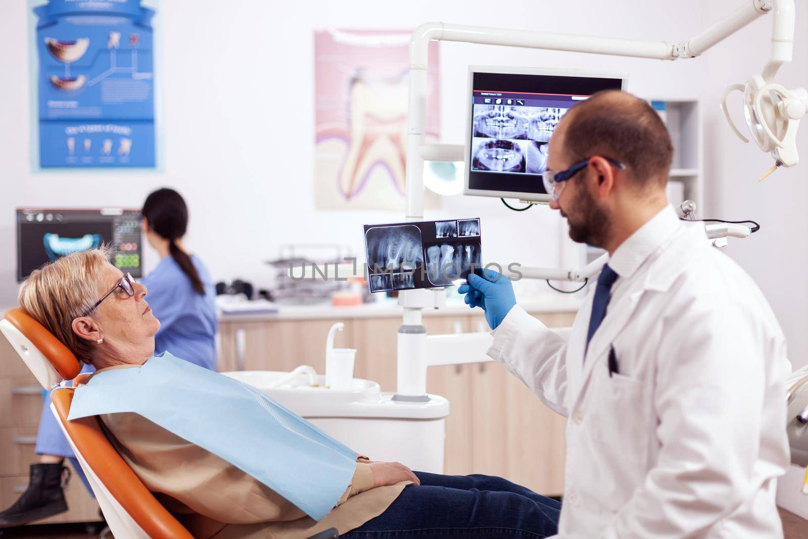 Dentist looking and examining at senior woman dental radiography by DCStudio