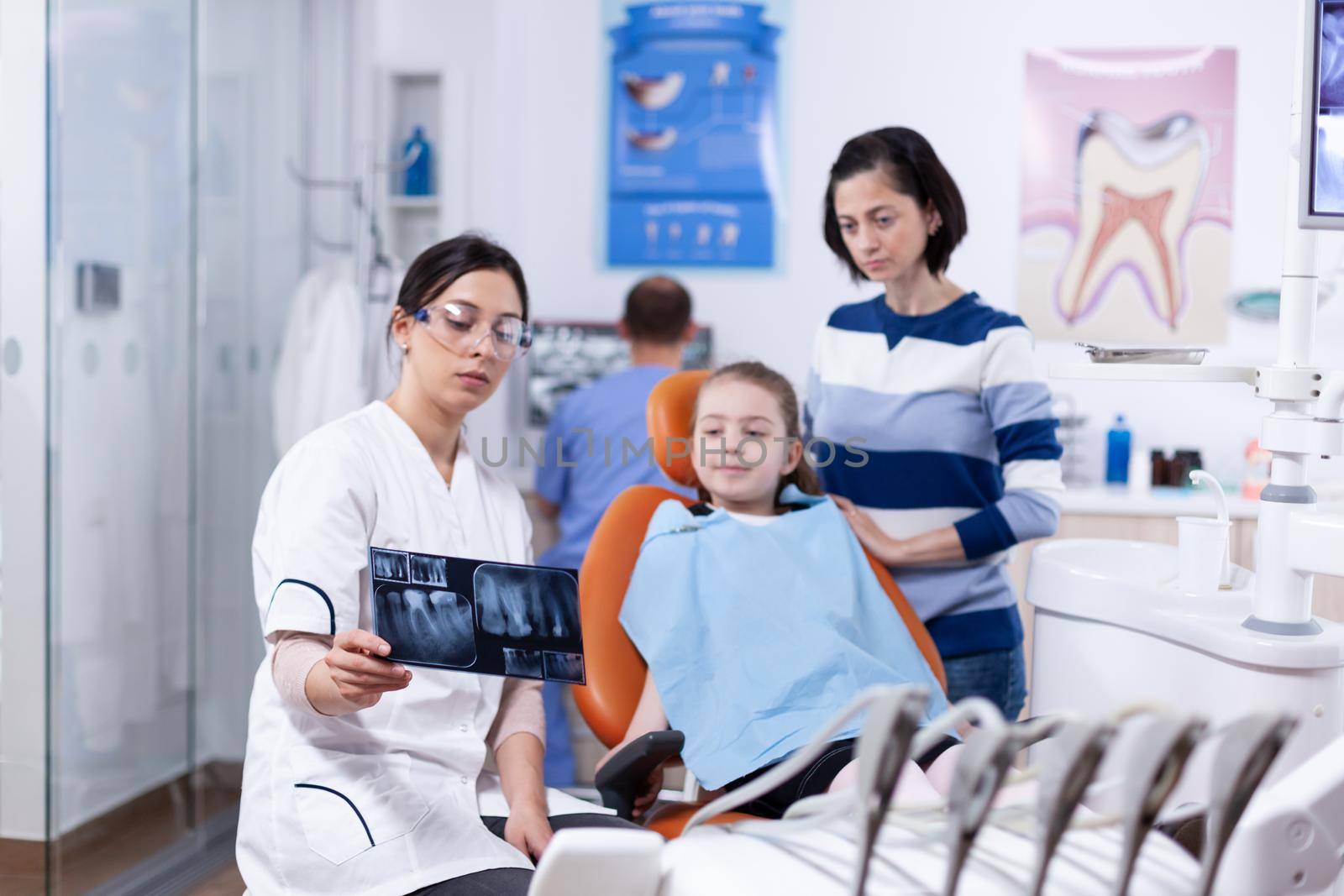Parent and kid in dentistiry office looking at dental radiography by DCStudio