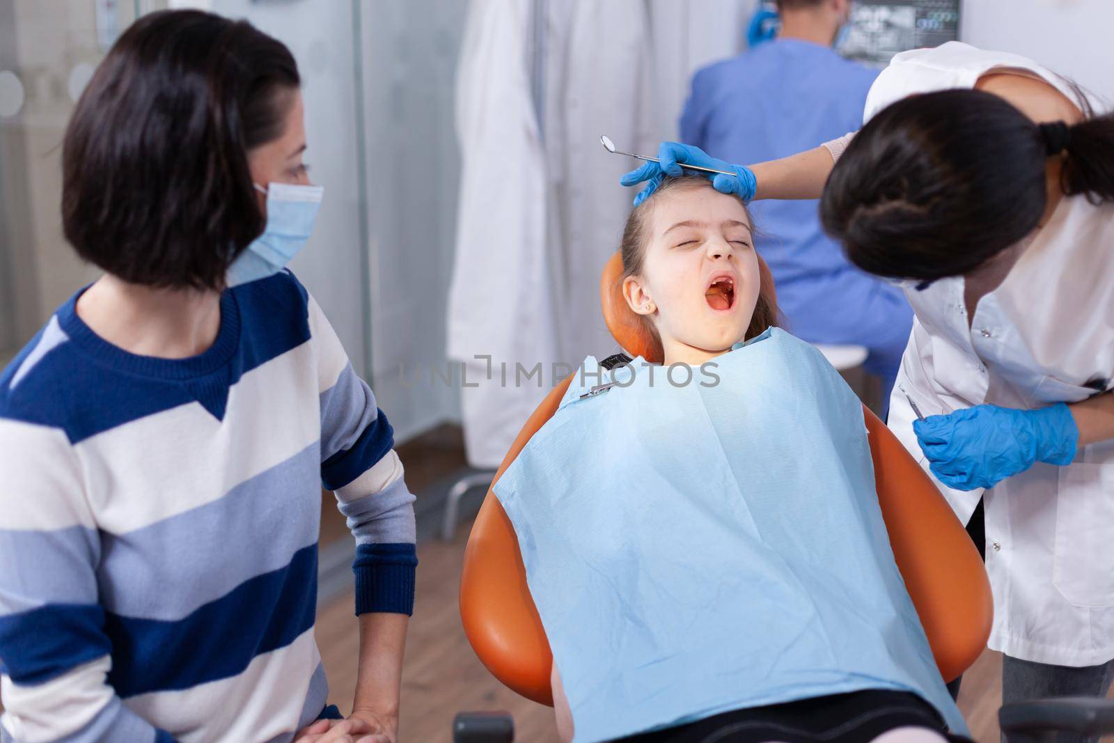 Dental doctor checking tooth hygine of kid by DCStudio