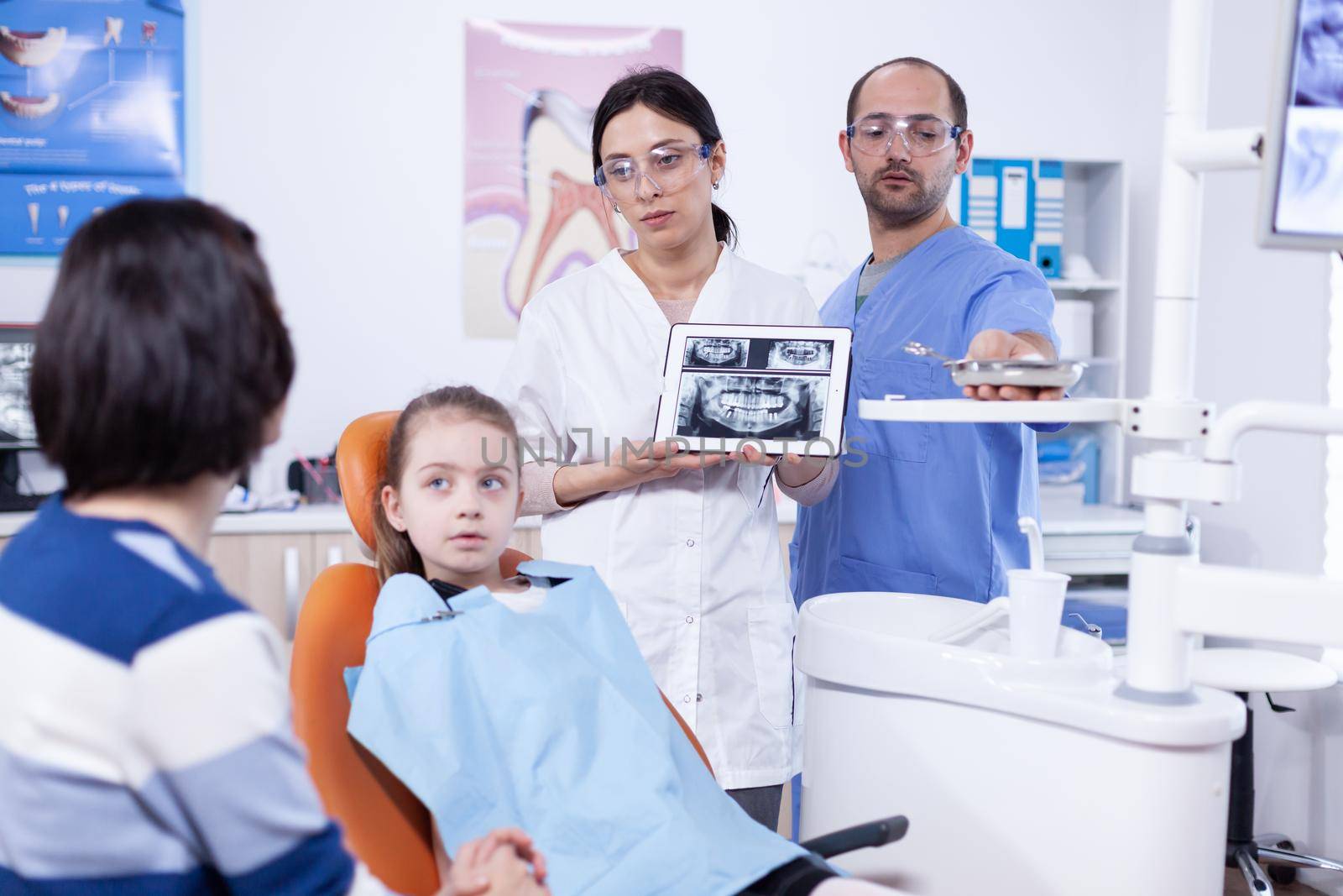 Pediatric dentist discussing about cavity prevention with parent of little girl by DCStudio
