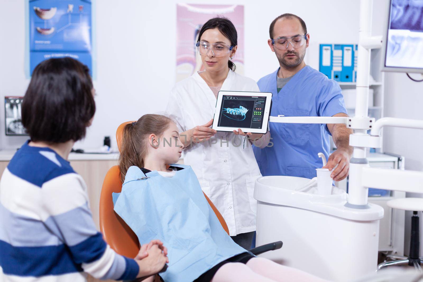 Dentist in dentistiry office showing tablet pc with jaw radiography by DCStudio