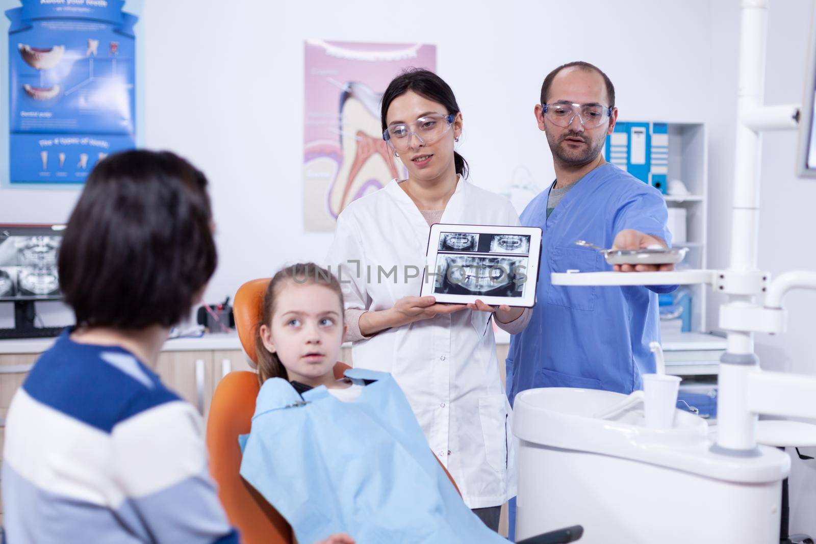 Dentist discussing about cavity prevention with little girl parent by DCStudio